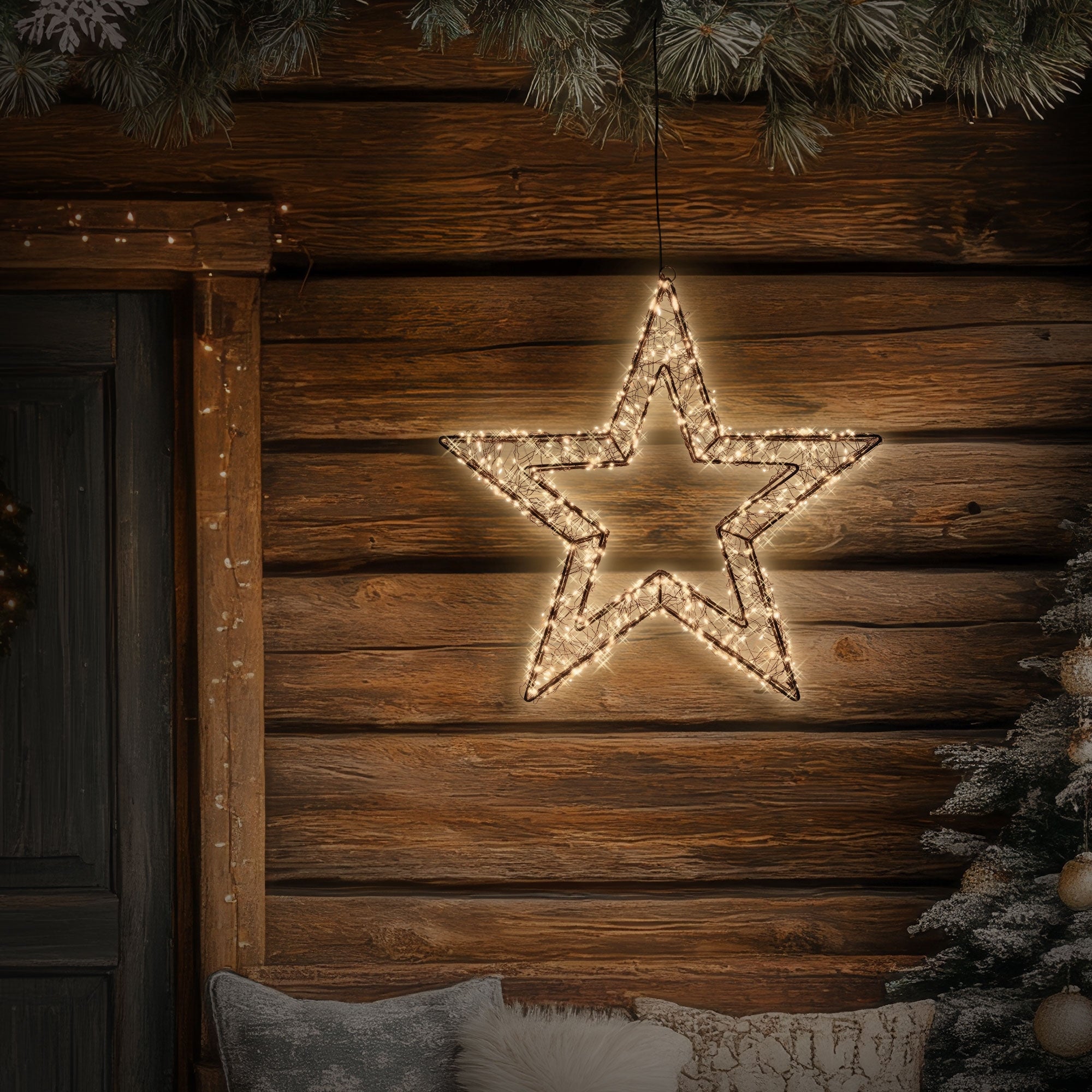 Une étoile brillante pend devant un revêtement en bois, entourée de branches de sapin.