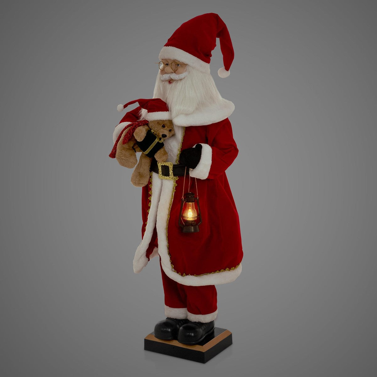 Una figura di Babbo Natale vestita di rosso, con un orsacchiotto e una lanterna.