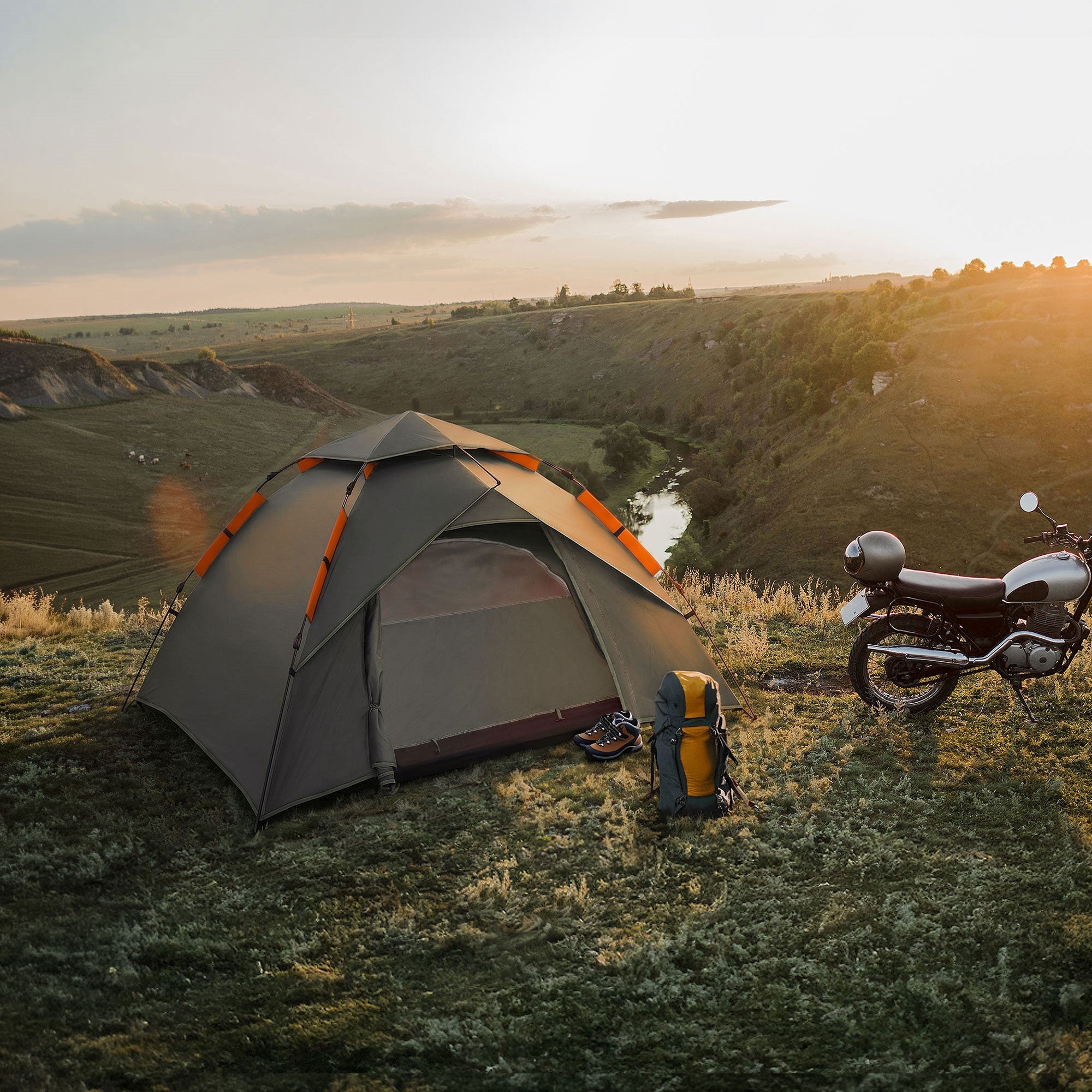 Zelt auf einer Wiese mit Motorrad und Rucksack in der Nähe.