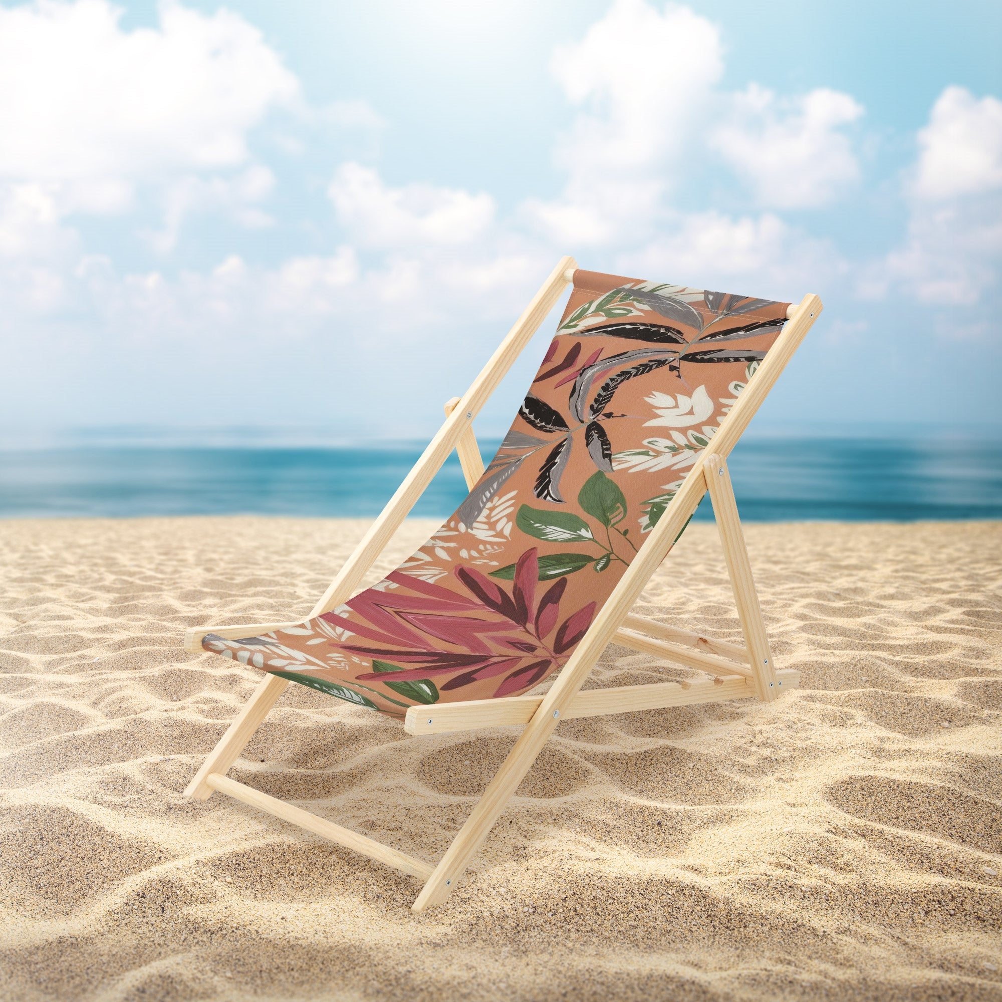 Liegestuhl am Strand mit floralem Muster und Himmel im Hintergrund.