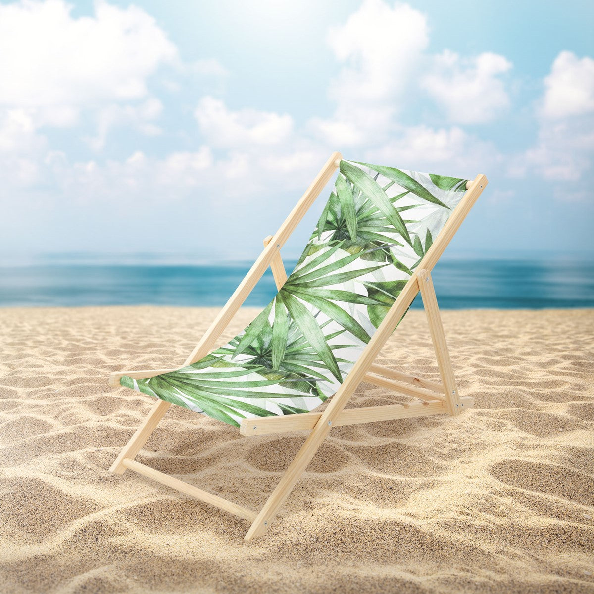 Ligstoel op het strand met een palmboompatroon en de zee op de achtergrond.