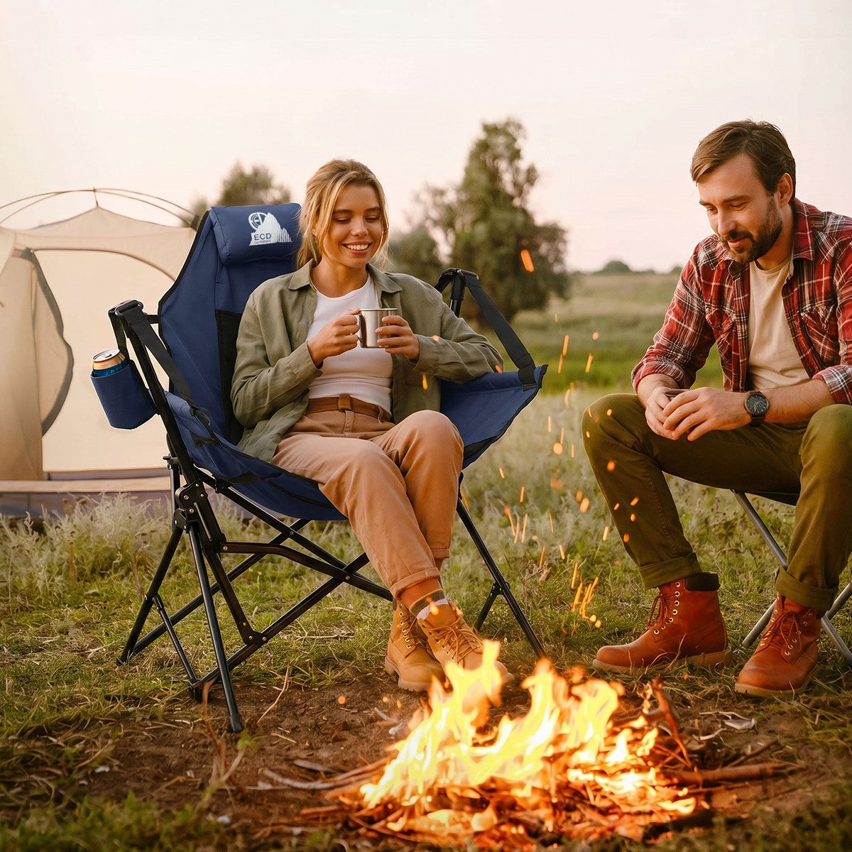 Zwei Personen sitzen am Lagerfeuer, eine hält eine Tasse.