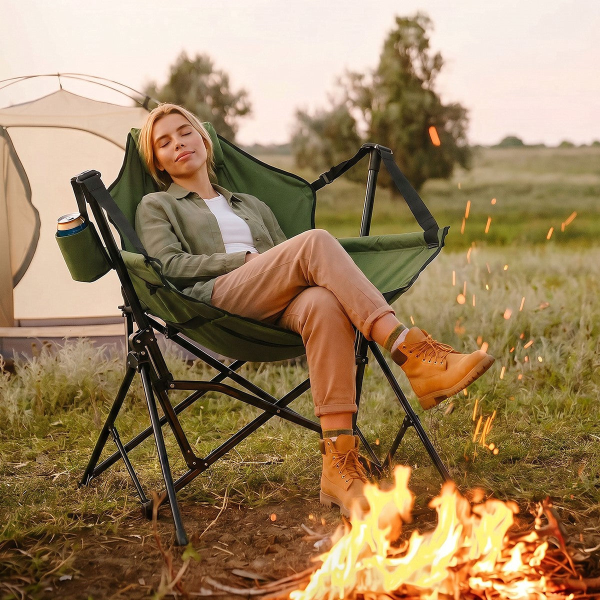Frau sitzt entspannt in einem grünen Campingstuhl neben einem Lagerfeuer.