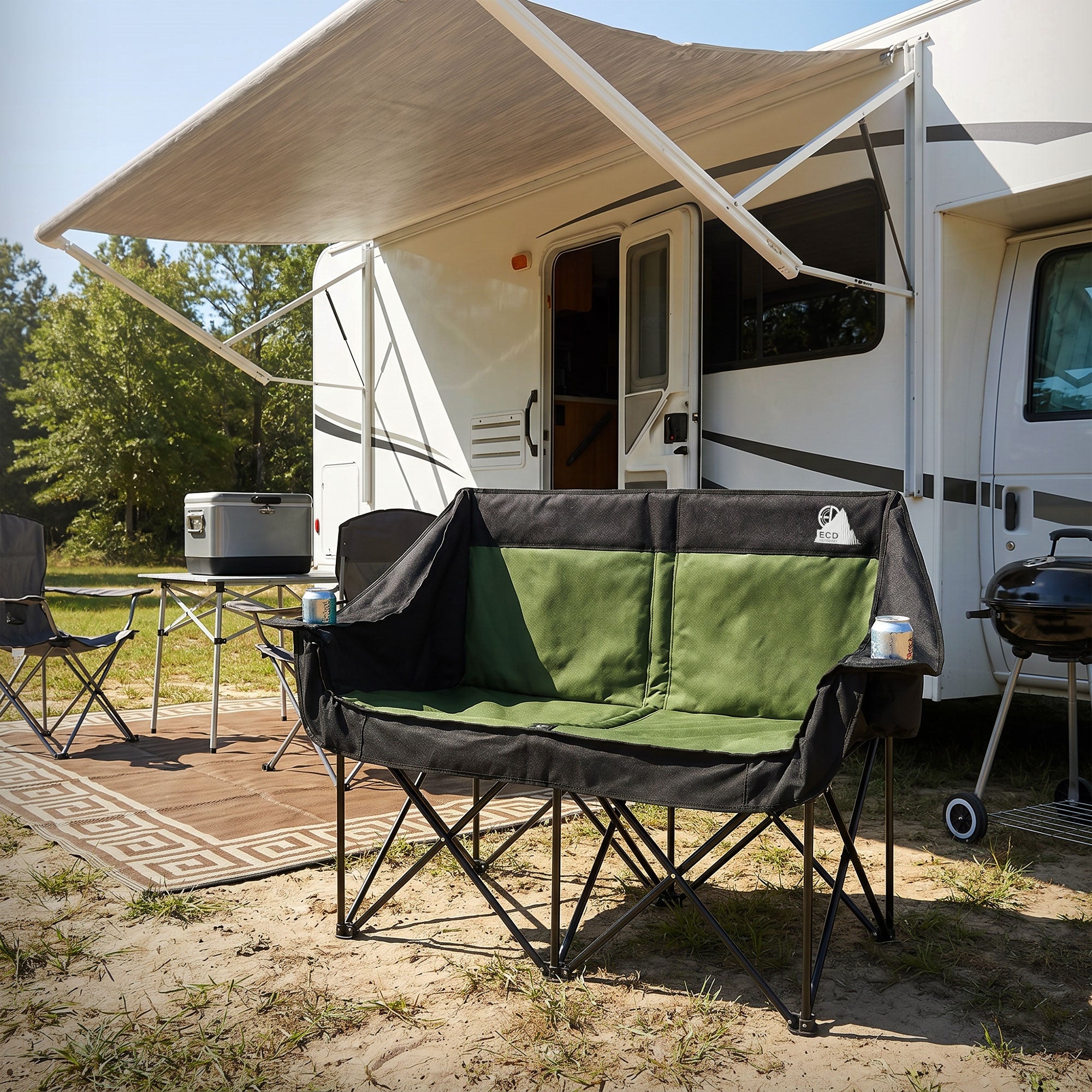 Zwei Personen sitzen auf einem grünen Campingstuhl vor einem Wohnmobil.
