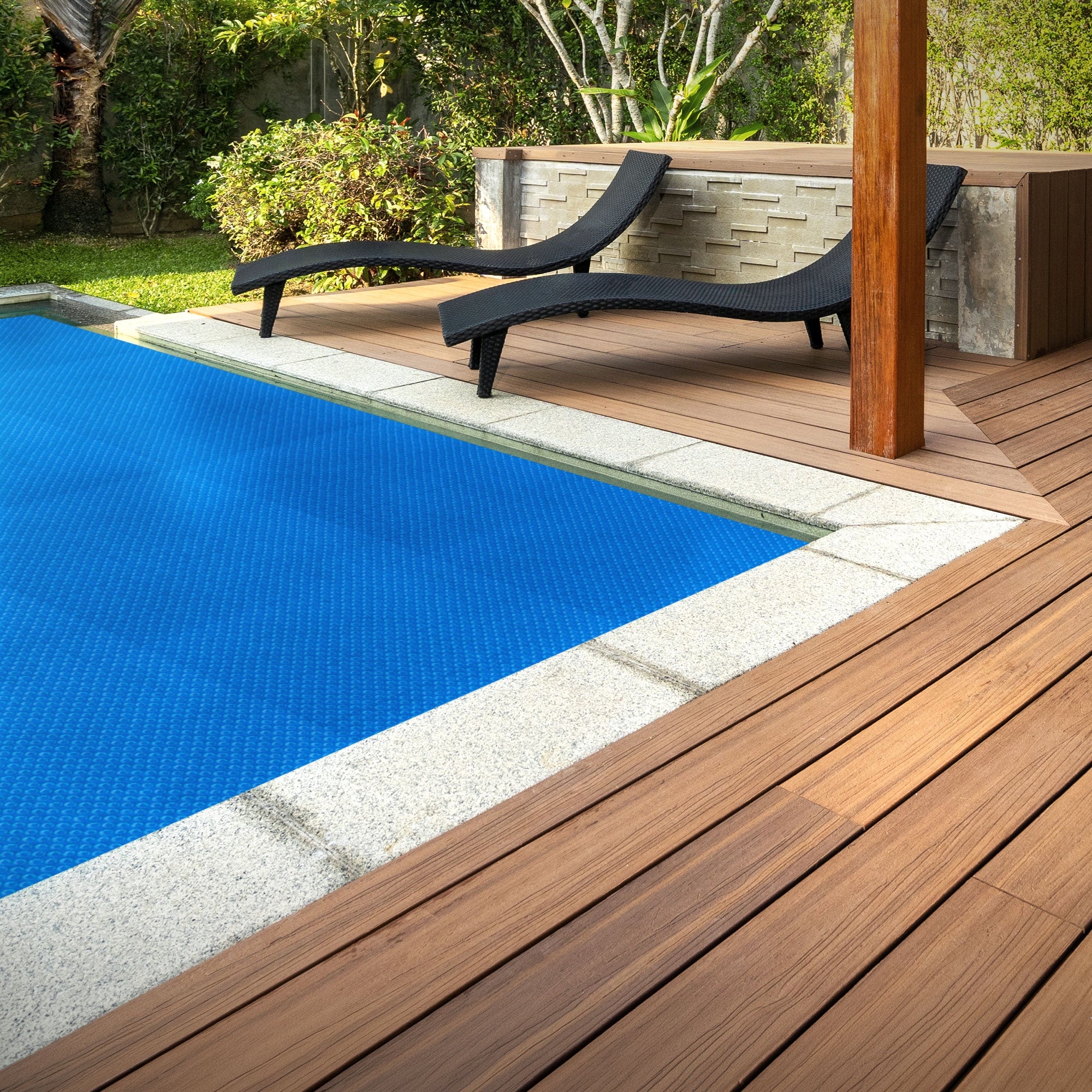 Zwei schwarze Liegen neben einem blauen Pool auf einer Holzterrasse.