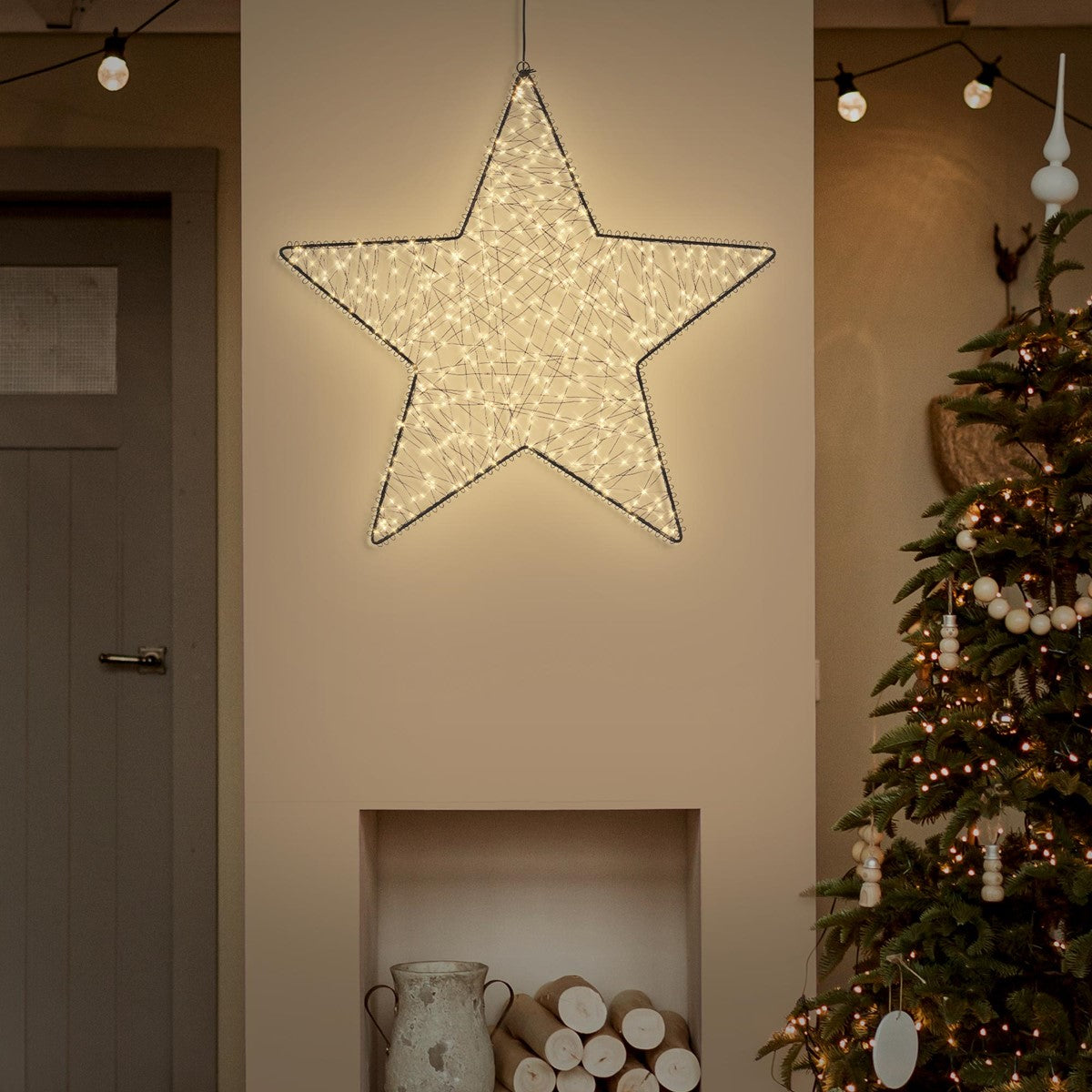 Leuchtender Stern hängt an der Wand über einem Weihnachtsbaum