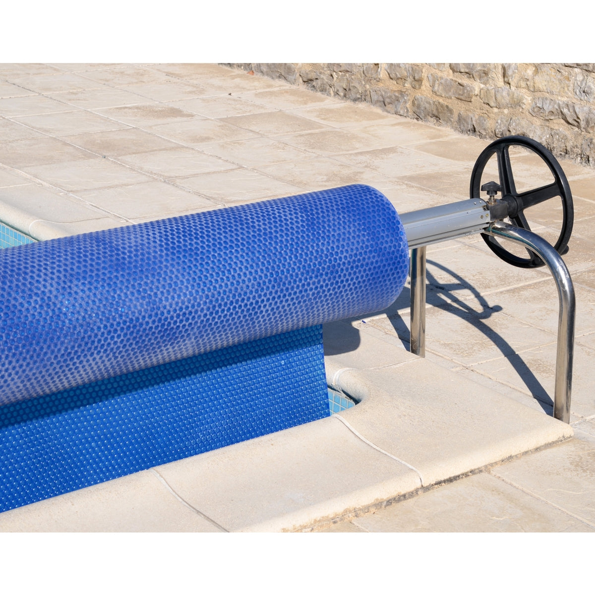 Blauer Poolabdeckungsroller auf einem Steinboden neben einem Pool.