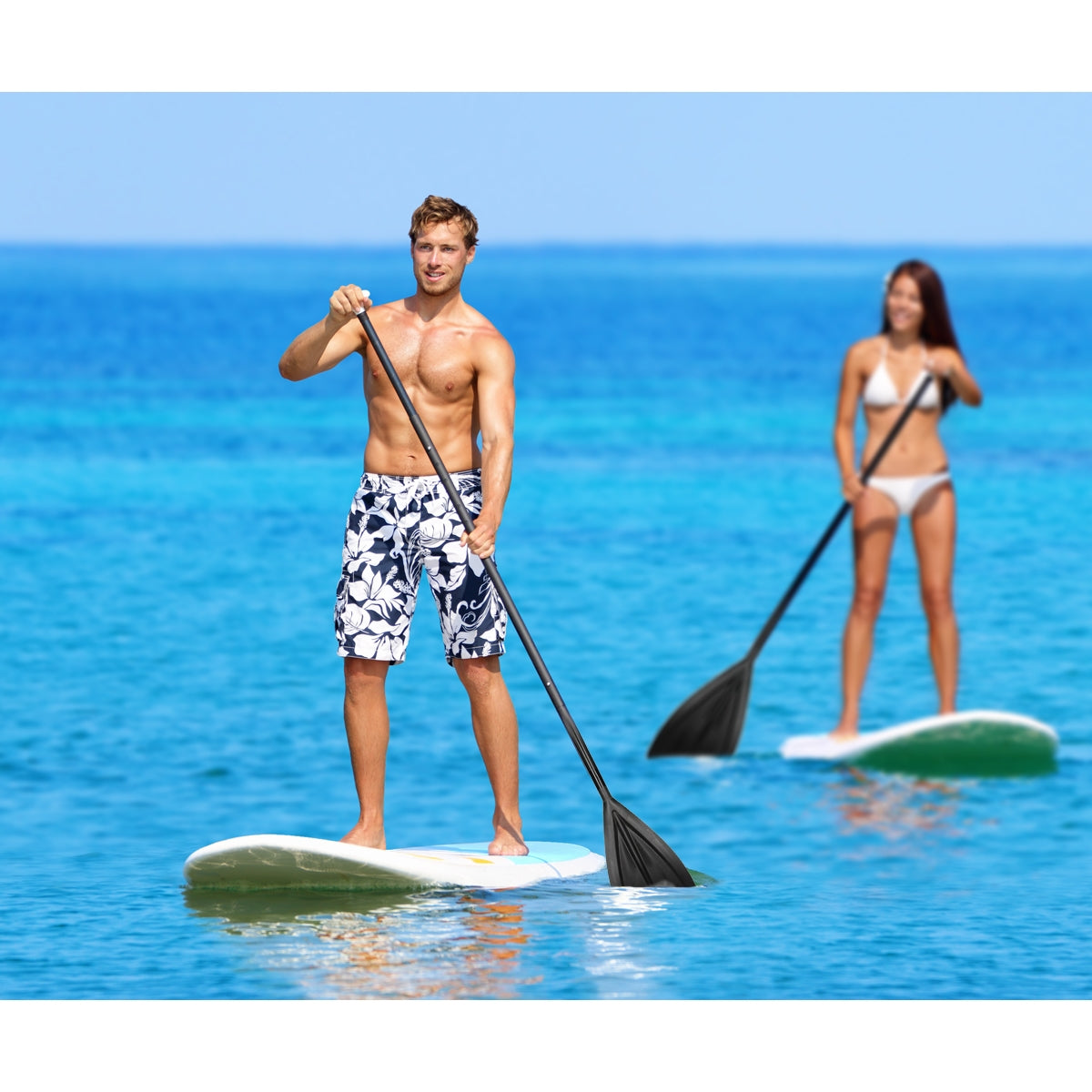Twee personen peddelen op stand-up paddleboards in het water.