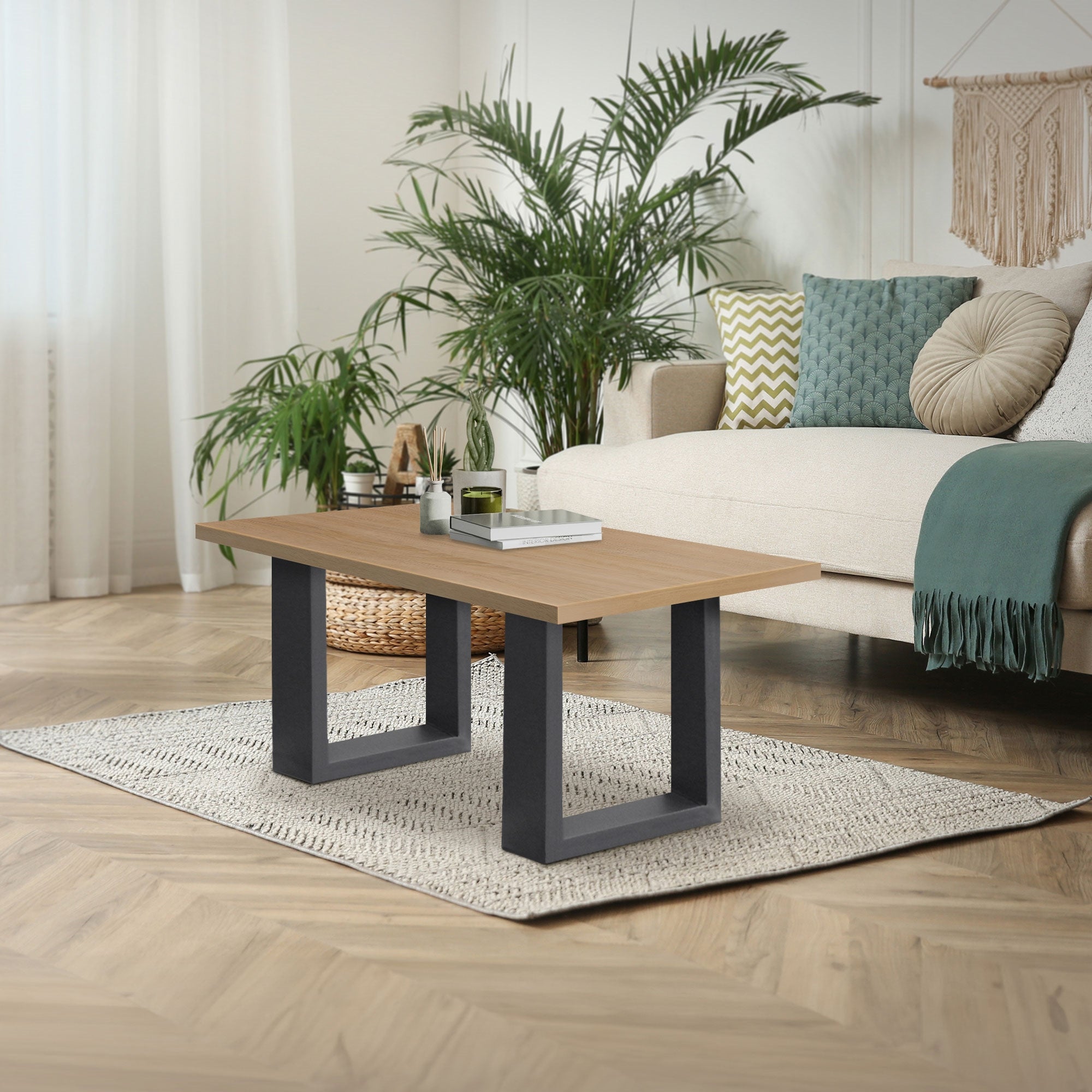 Moderne opholdsområde med et bord, sofa og planter i baggrunden.