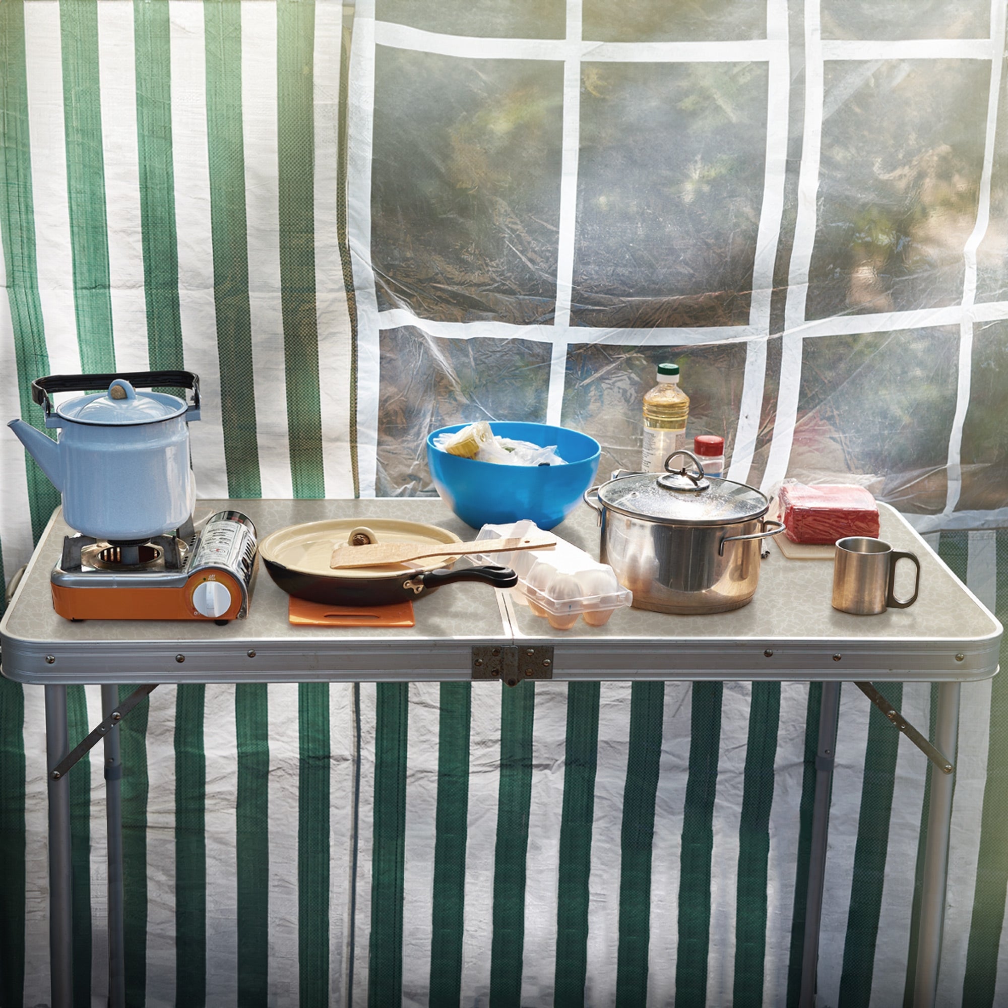 Camping stove, pots, and food on a table in the tent.