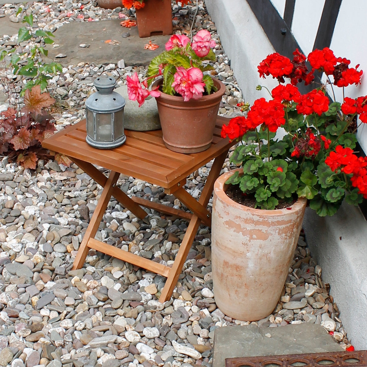 Petite table avec des plantes et une lanterne sur un sol en gravier.