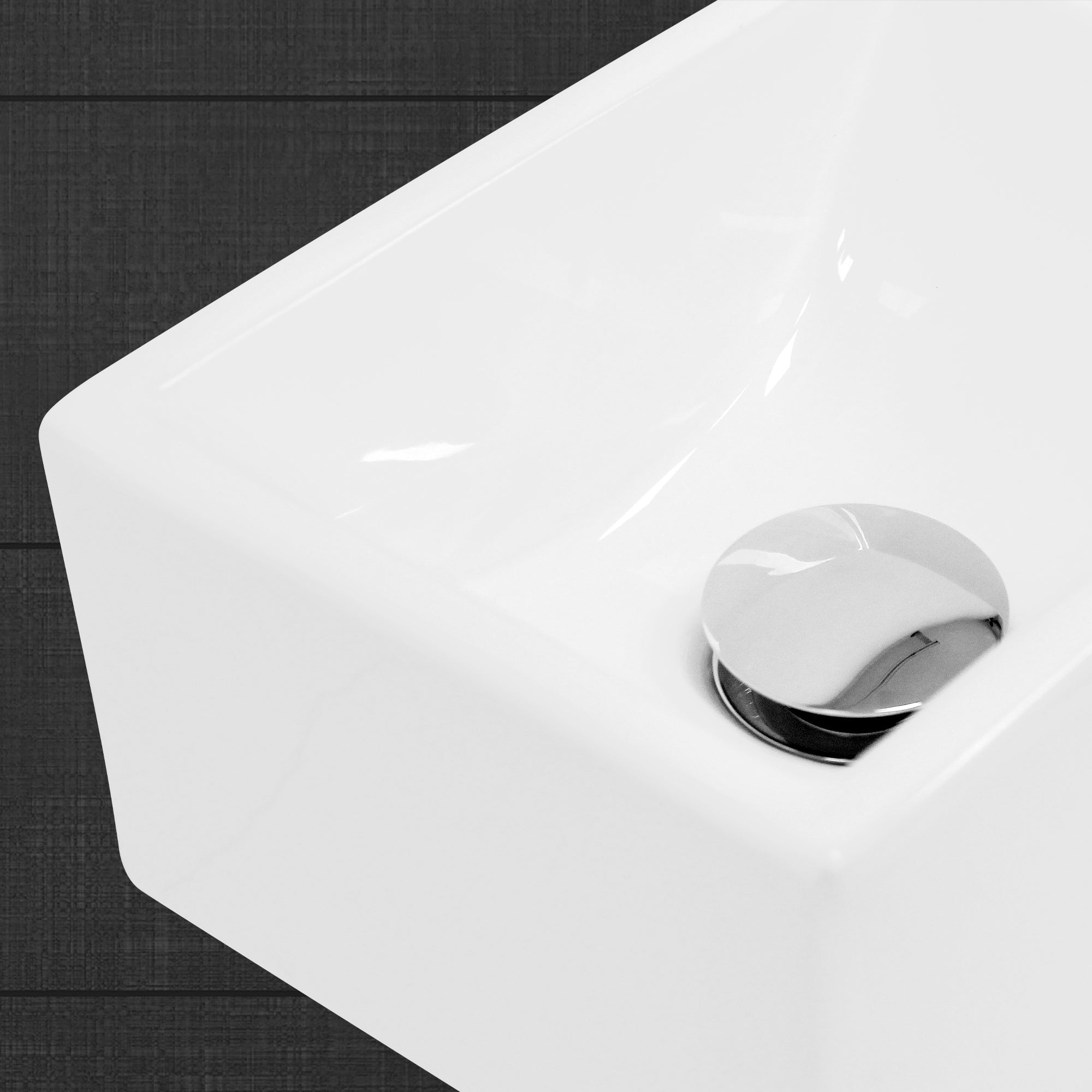 Close-up van een witte wastafel met een glanzend afvoerplug.
