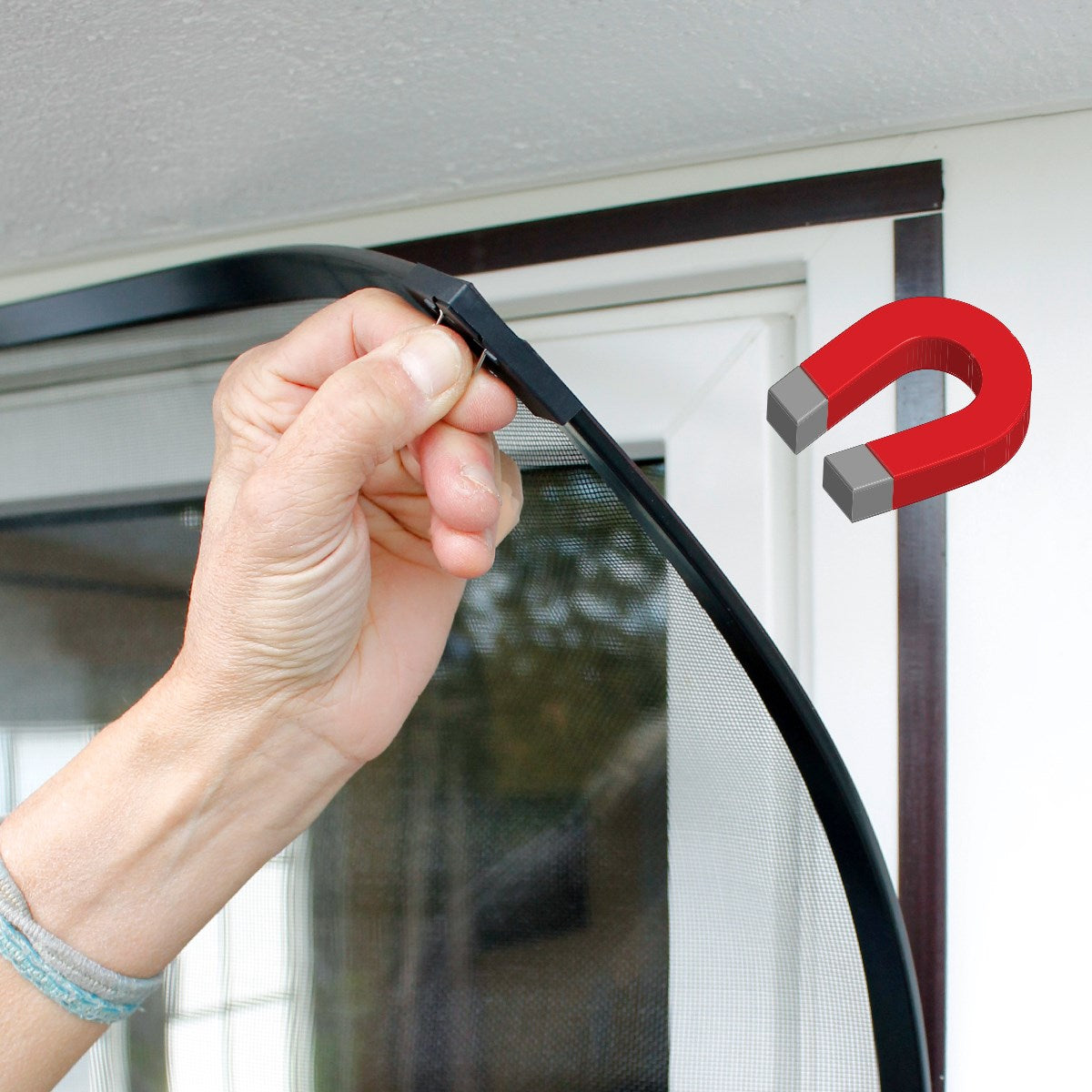A hand holds a flexible frame with a magnet against a window.
