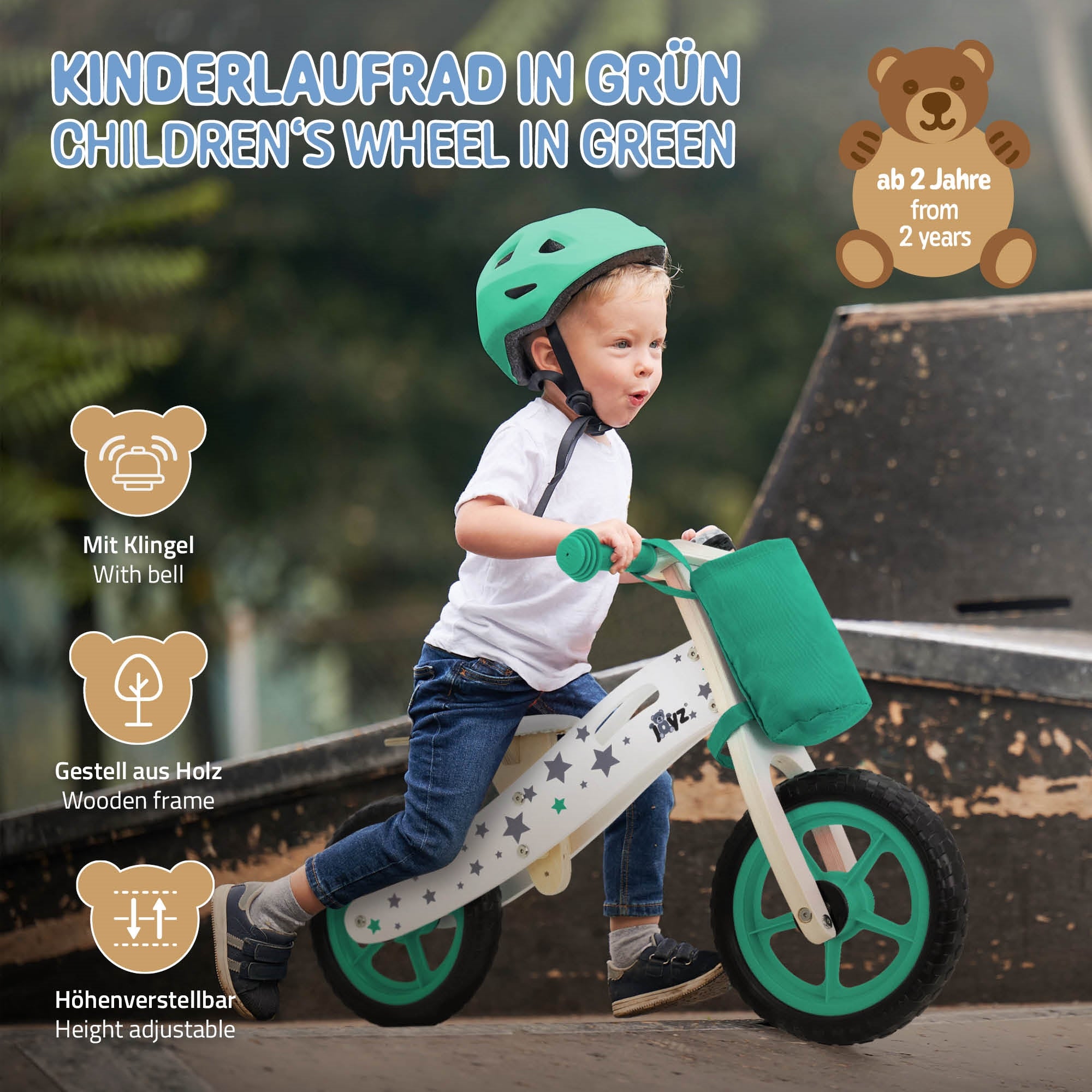 Kinderrad in Grün mit Helm, auf einem Spielplatz, mit Holzrahmen und Klingel.