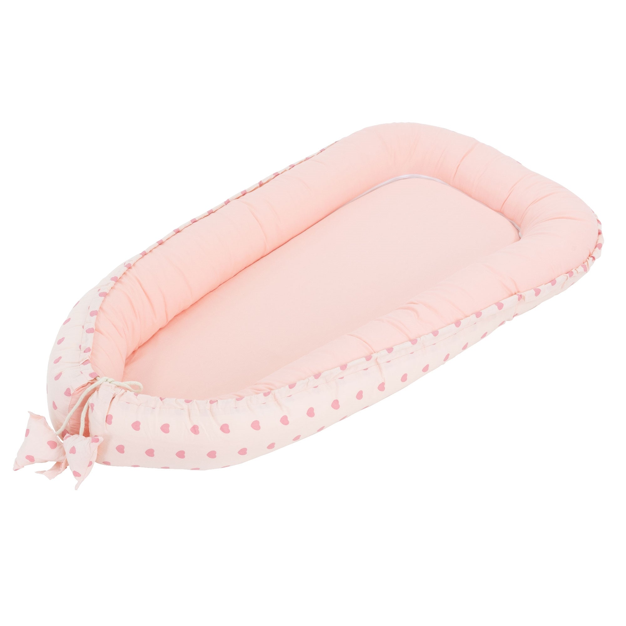 Coussin rond avec des cœurs roses sur fond blanc.