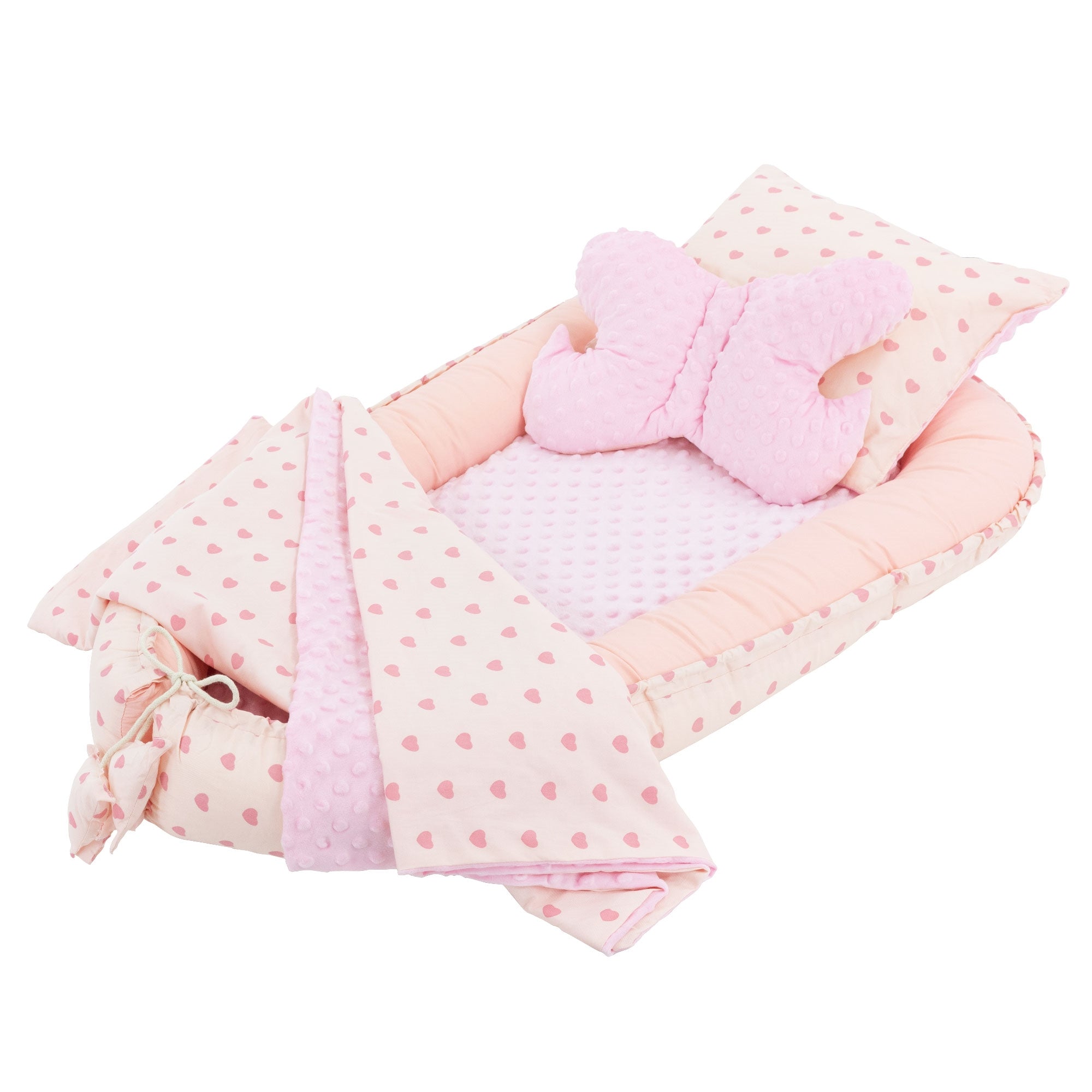 Un lit pour bébé avec couverture rose et coussin en forme de papillon.