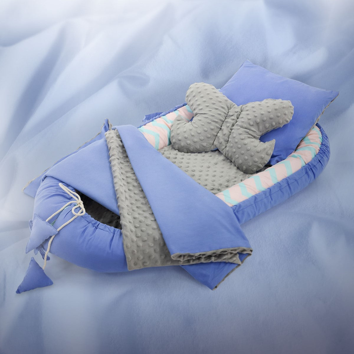 Babybett in Blau mit Kissen und Decke auf einem hellen Hintergrund.