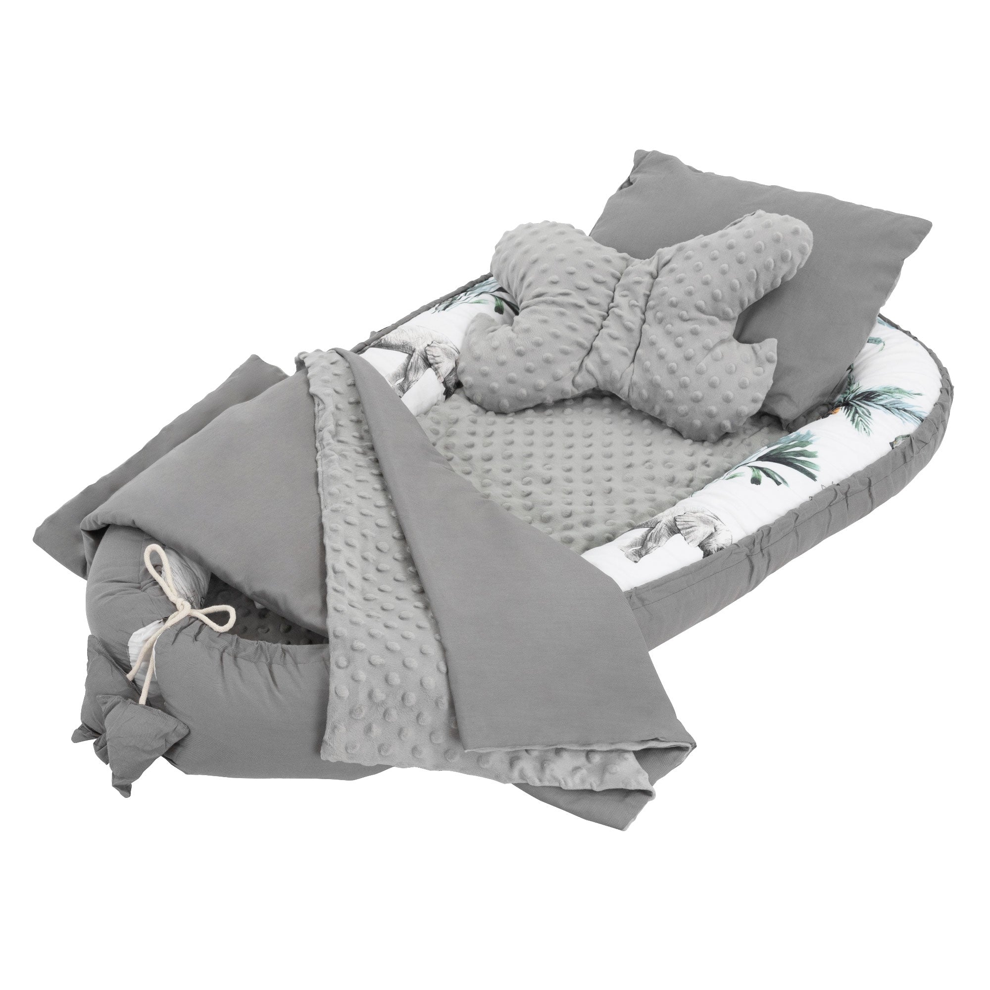 Berceau avec couverture grise et coussin, entouré d'un environnement clair.