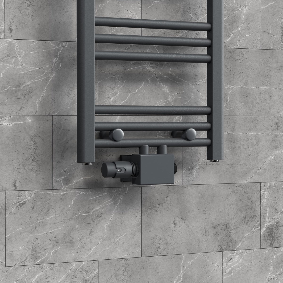 Radiador con termostato sobre un azulejo gris de pared.