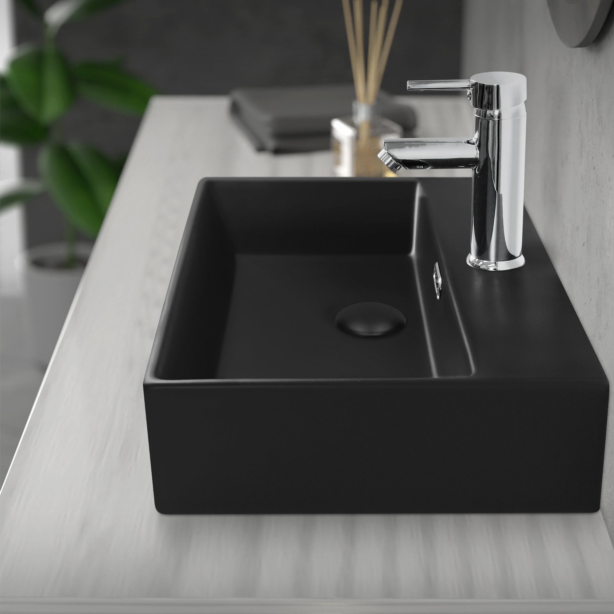 Schwarzes Waschbecken mit Wasserhahn auf einem hellen Tisch.