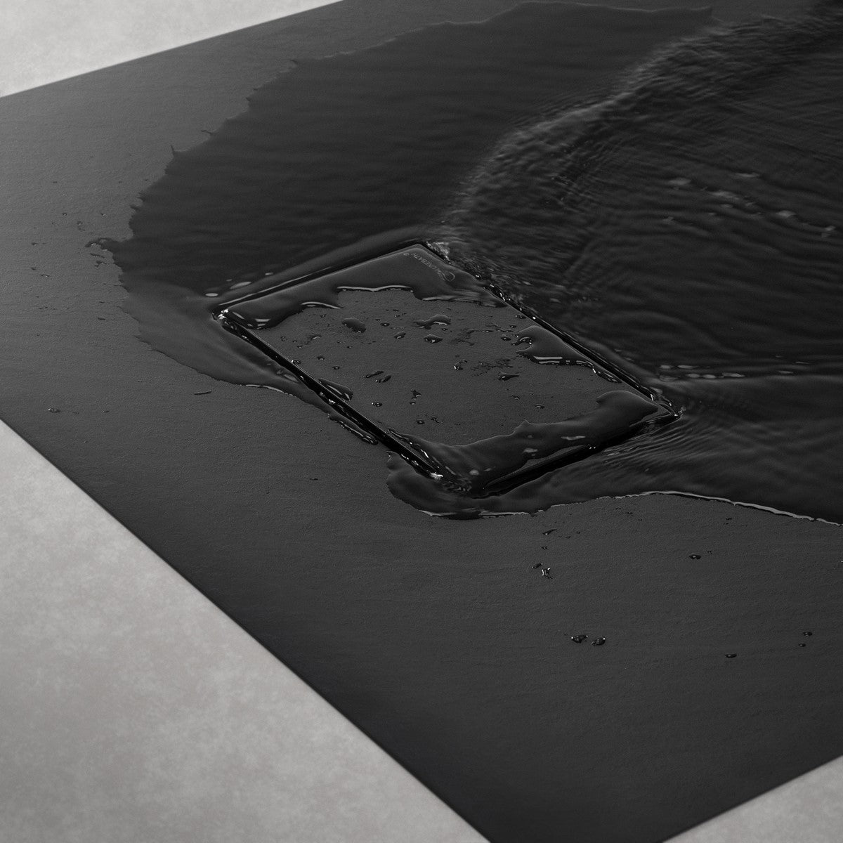 Plato de ducha negro con agua, desagüe rectangular.