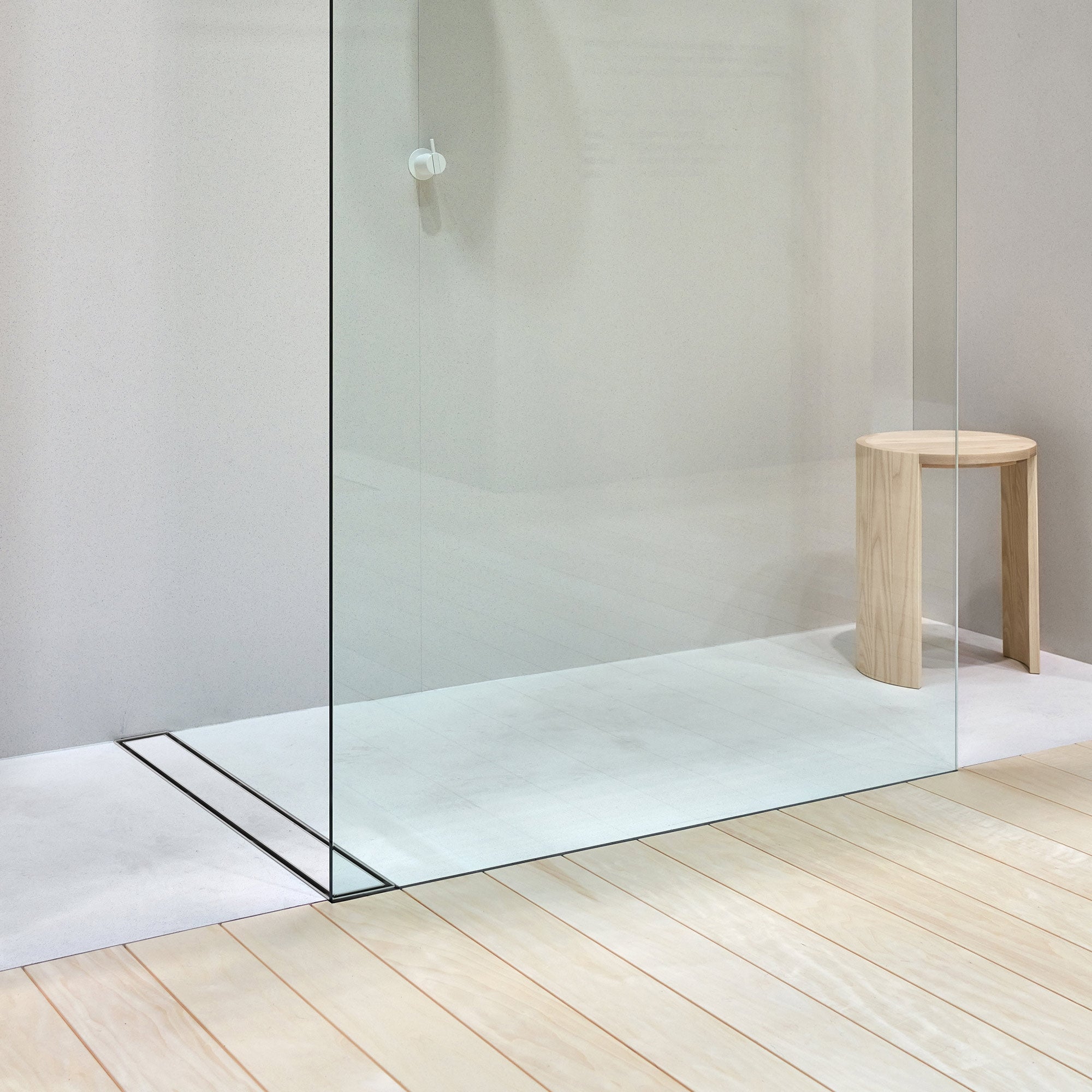 Glasdusche mit Duschrinne und Holzstuhl im Badezimmer.