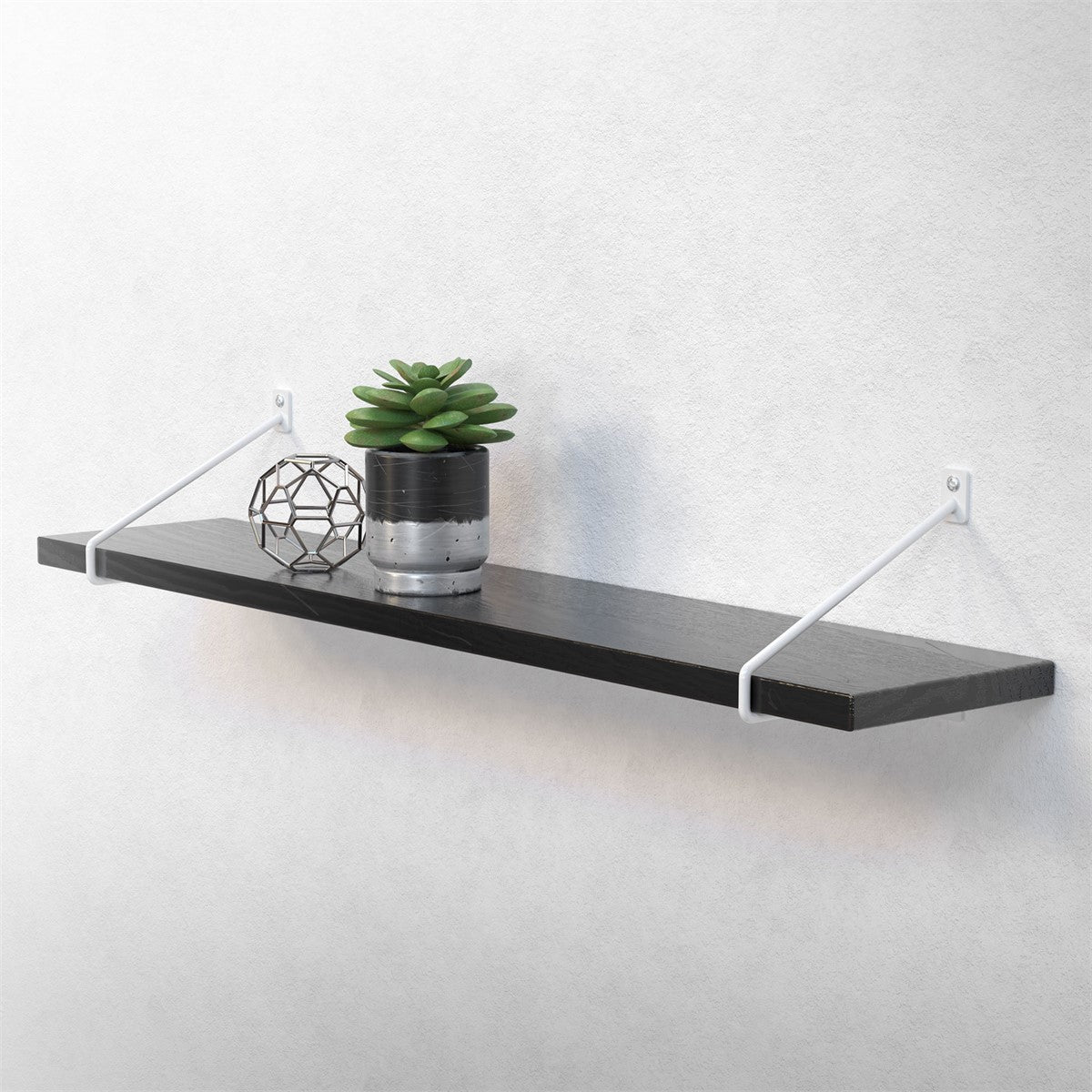 Black wall shelf with a plant and decorative object on a light-colored wall.
