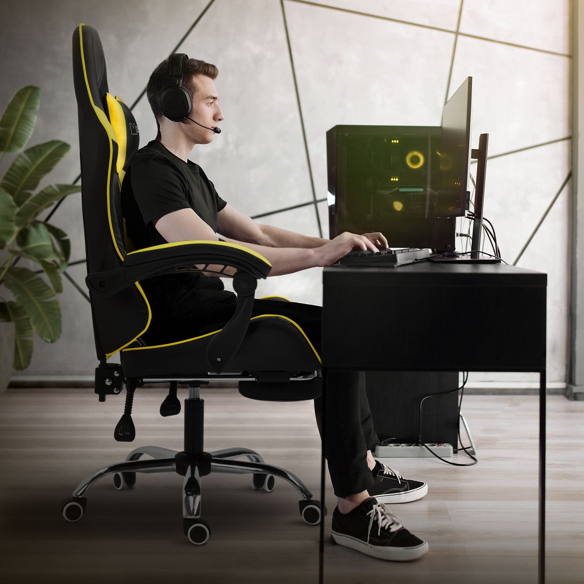 Jeune homme dans une chaise de gaming, jouant sur l'ordinateur avec un casque.