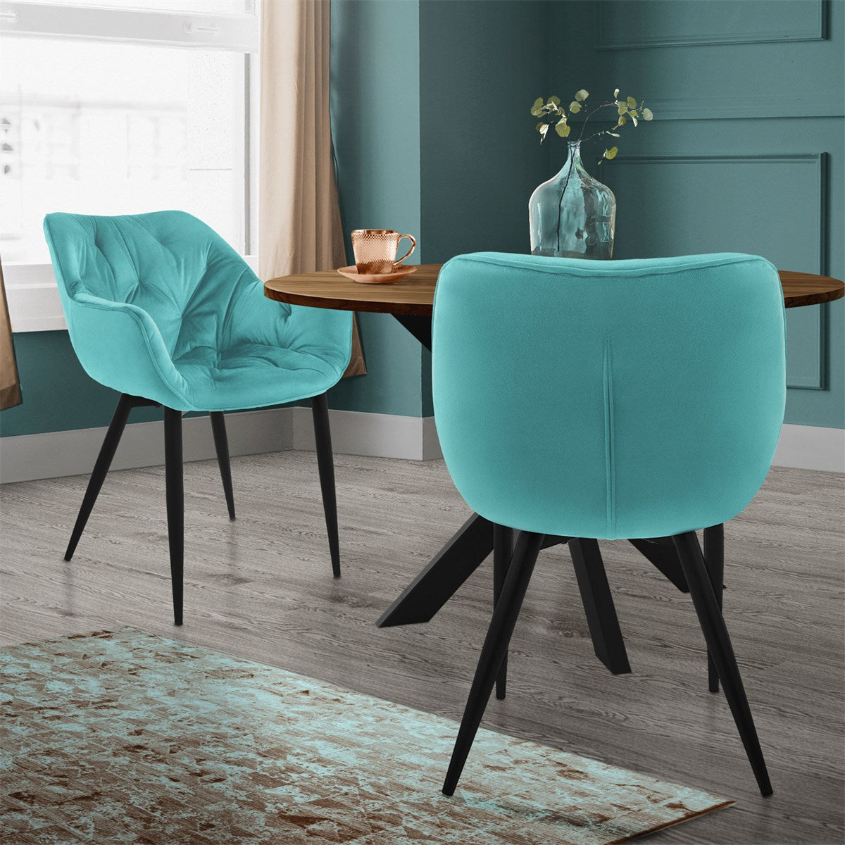 Two turquoise chairs at a table, with a vase and a copper cup.