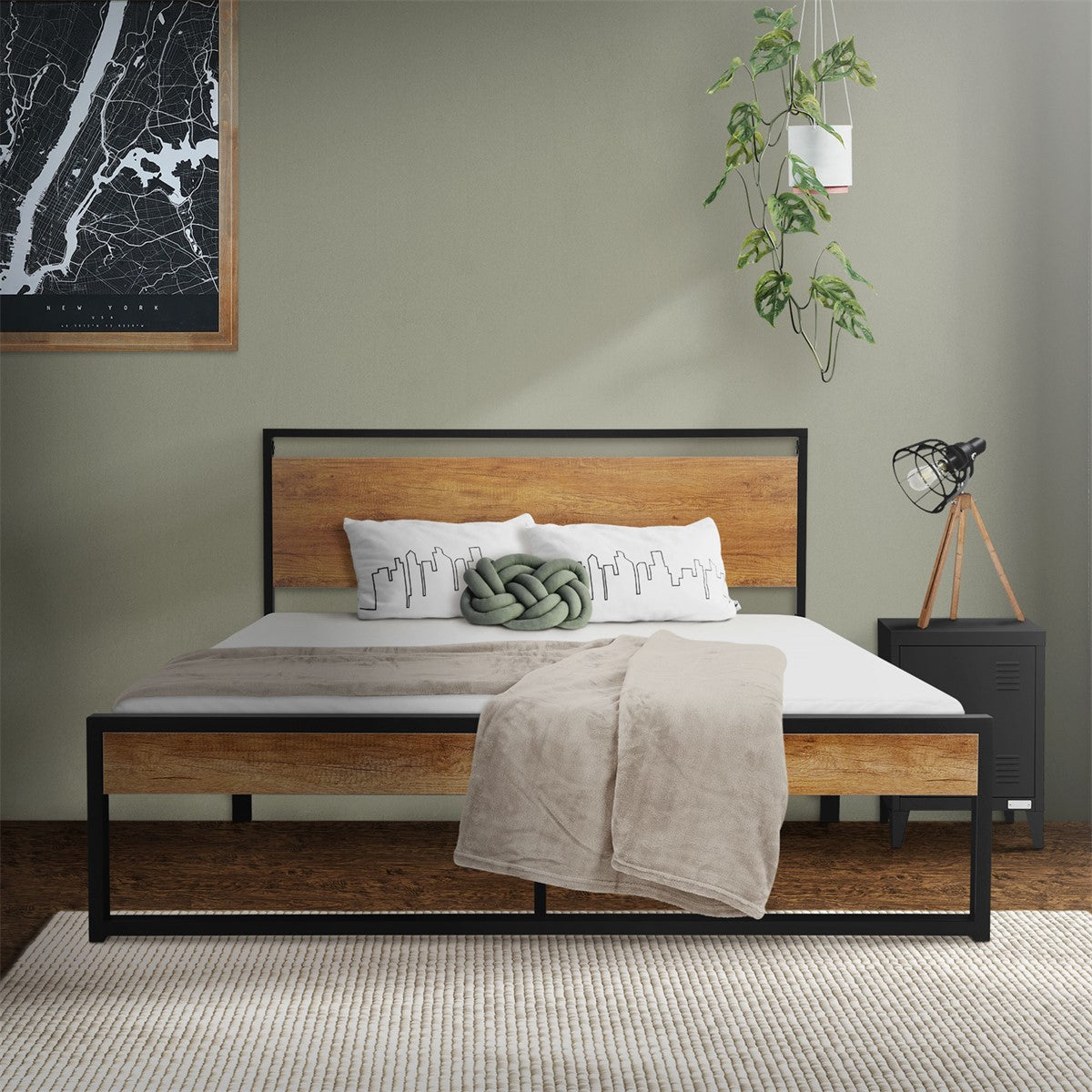 Metallbett im Raum, mit Kissen und Decke, Pflanzen und Lampe im Hintergrund.