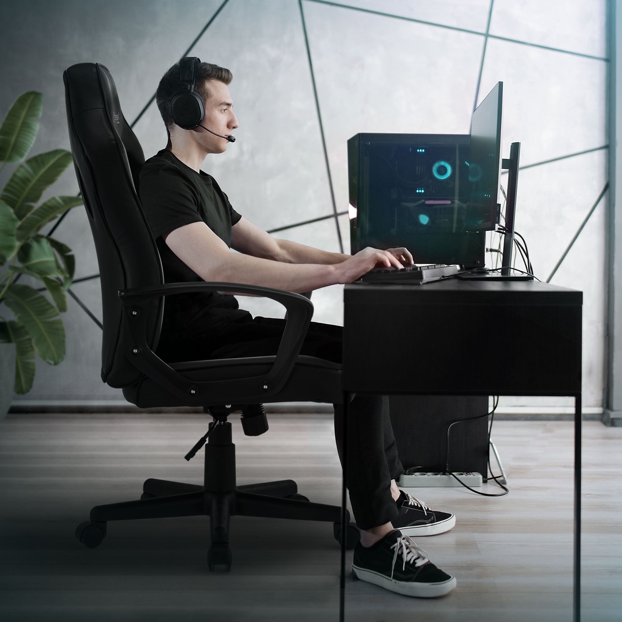 Homme assis à un bureau, portant des écouteurs et utilisant un ordinateur.