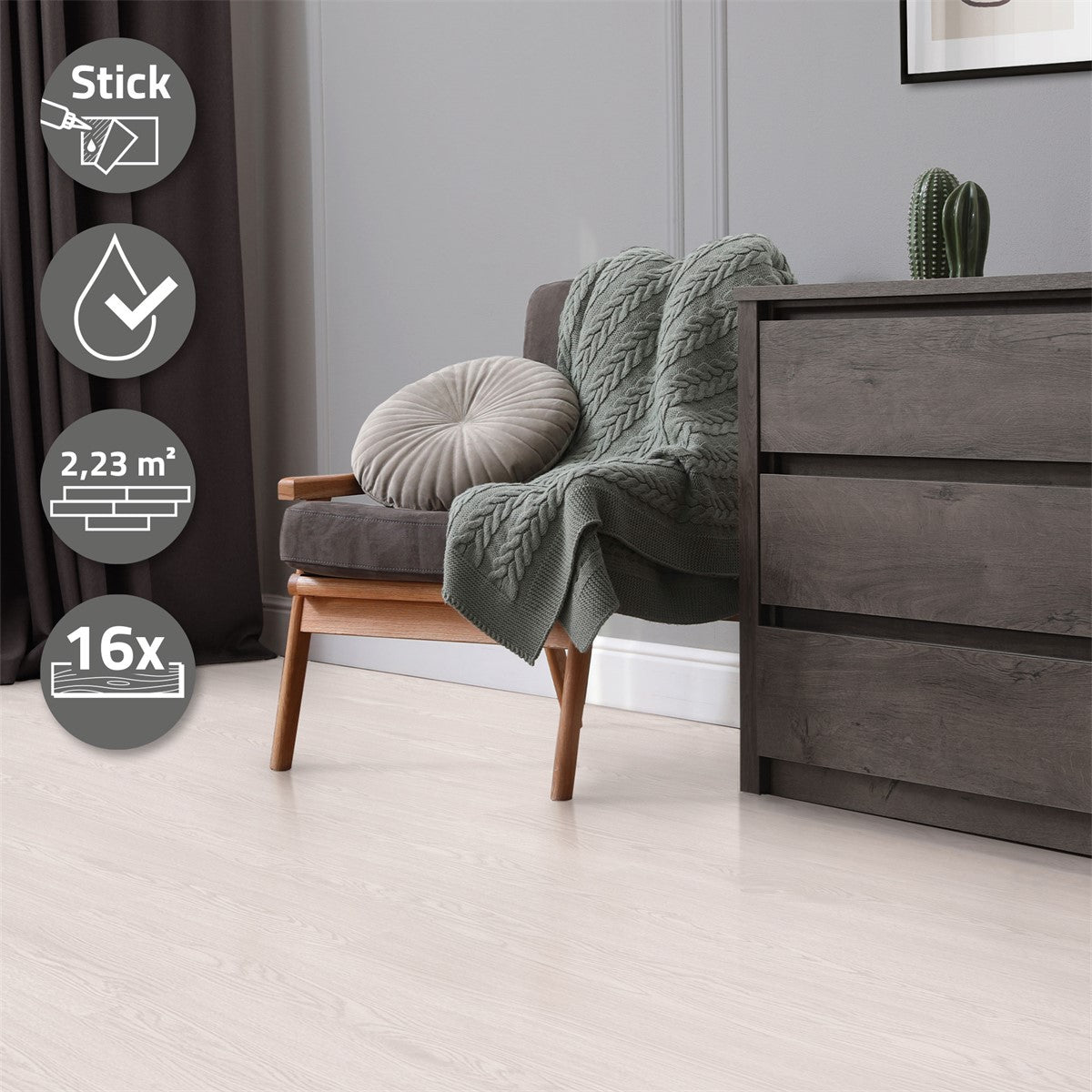 A gray armchair with a blanket and a cushion, next to a wooden cabinet on a light-colored floor.