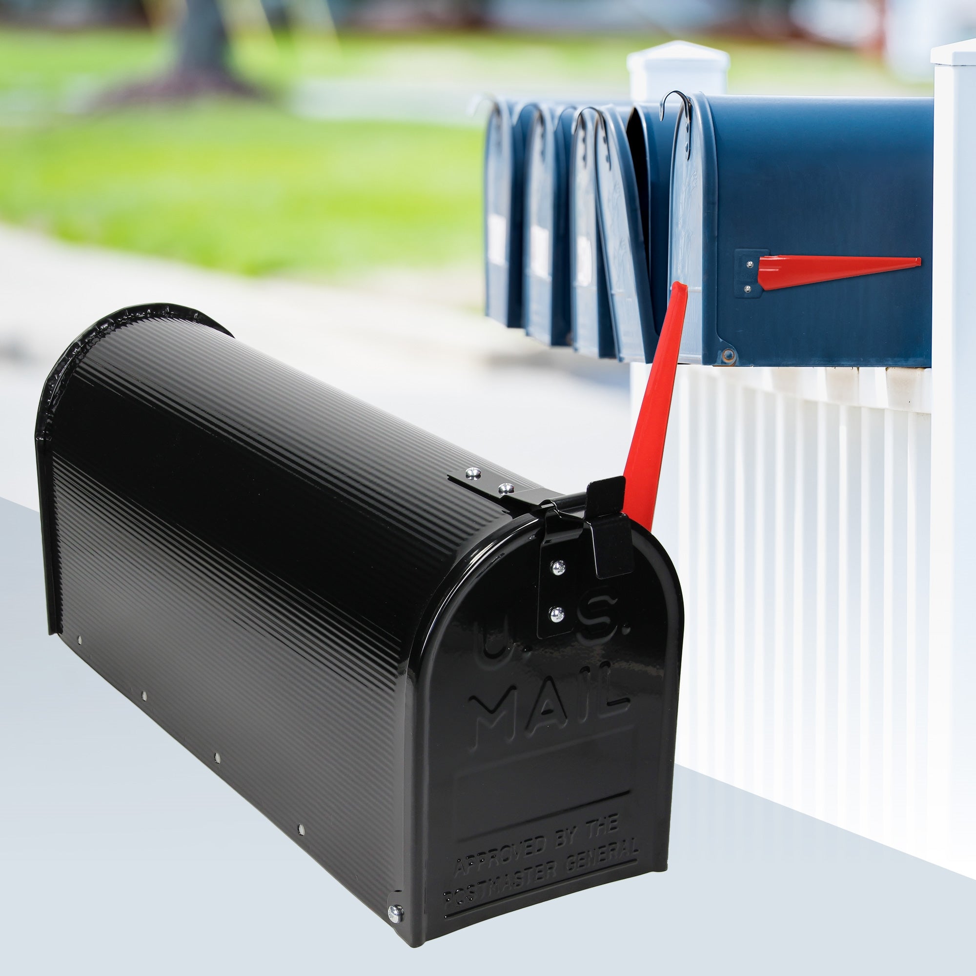 Schwarzer Briefkasten mit rotem Hebel, im Hintergrund mehrere Briefkästen in verschiedenen Farben.