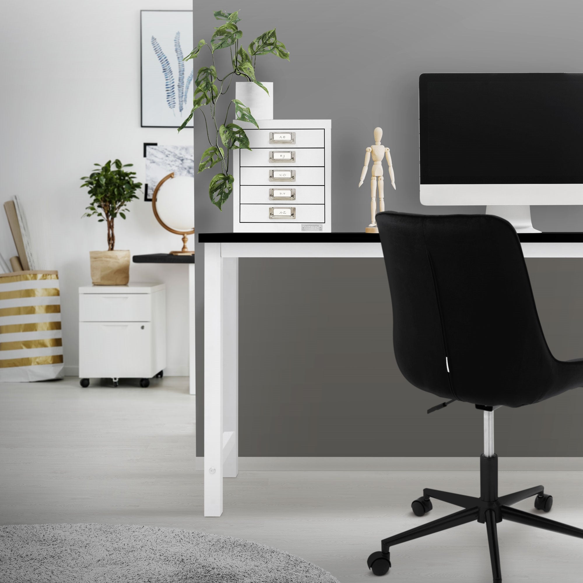 Büro mit weißem Aktenschrank, Computer und Pflanze auf dem Tisch.
