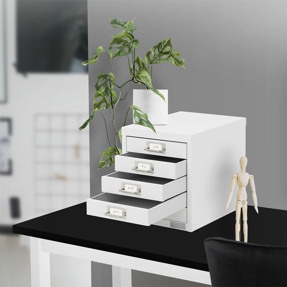 White cabinet with four drawers and a plant on a table.