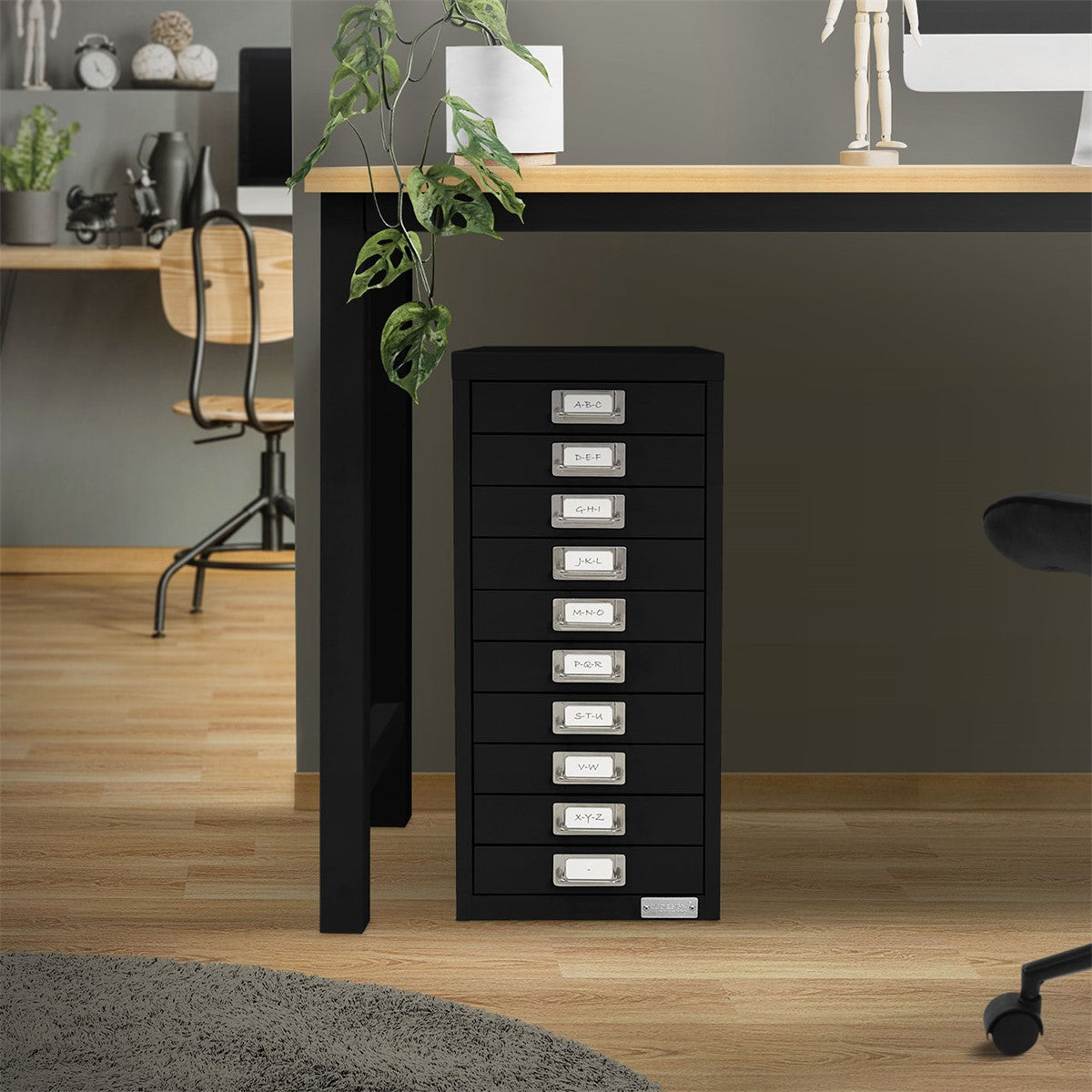Schwarzer Schrank mit Schubladen, steht neben einem Tisch in einem modernen Raum.