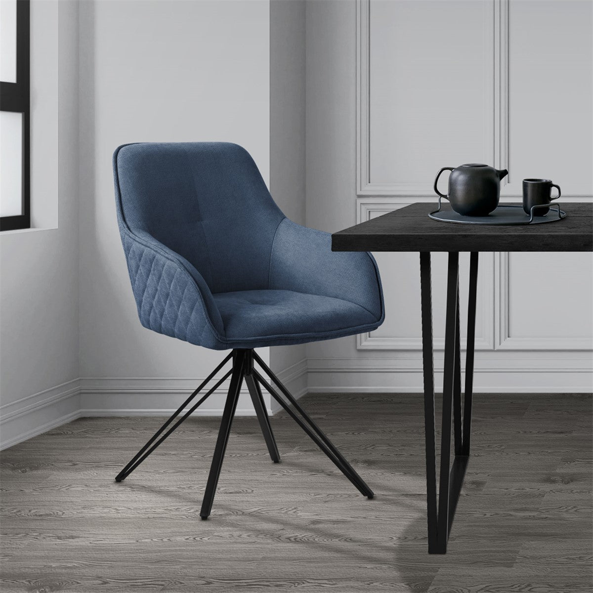 Blue chair at a table with a teapot and cup in a bright room.