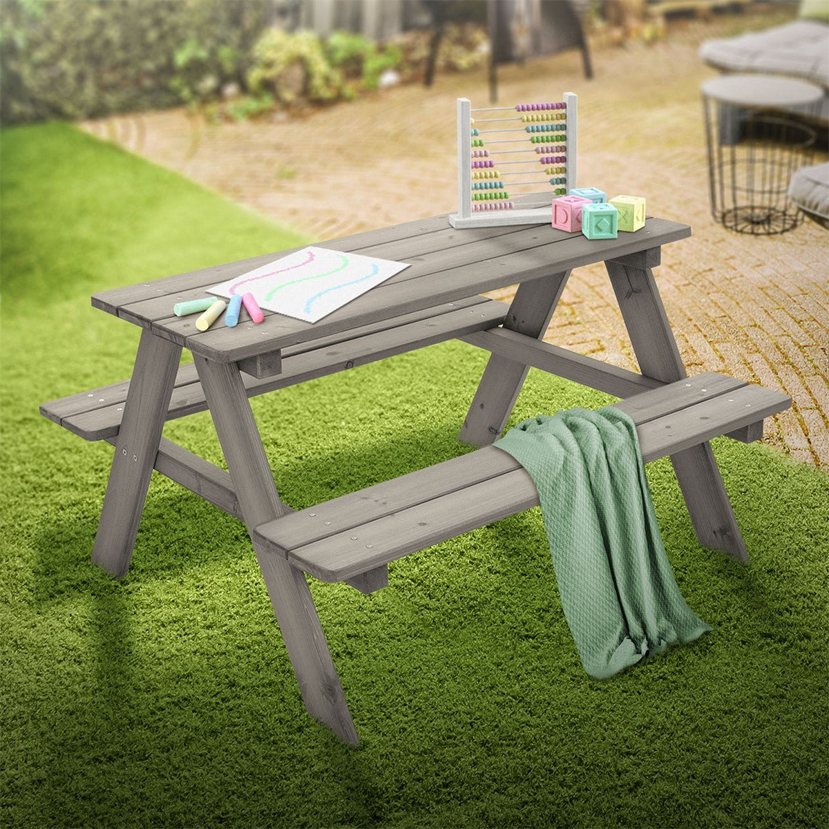 A gray table outdoors with toys and a blanket.