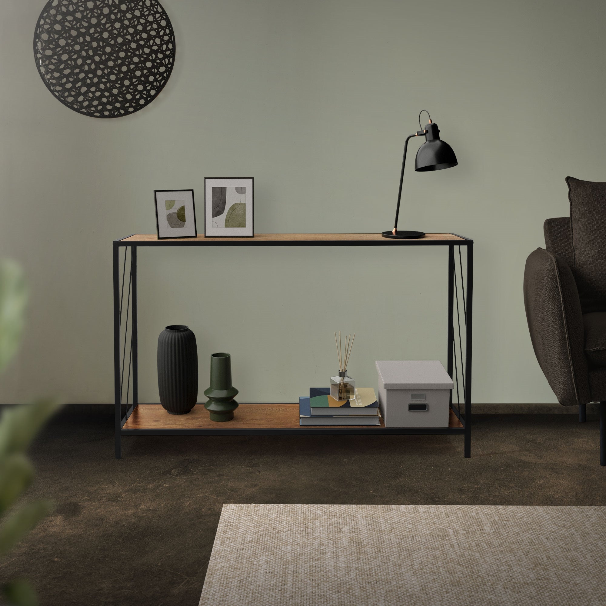 Ein Tisch mit Dekoration, Bildern und einer Lampe vor einer grünen Wand.