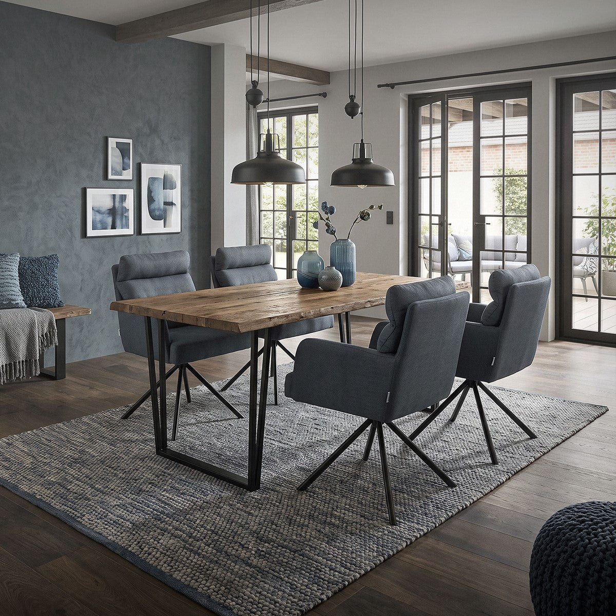 Salle à manger avec une table en bois et des chaises grises sur un tapis.