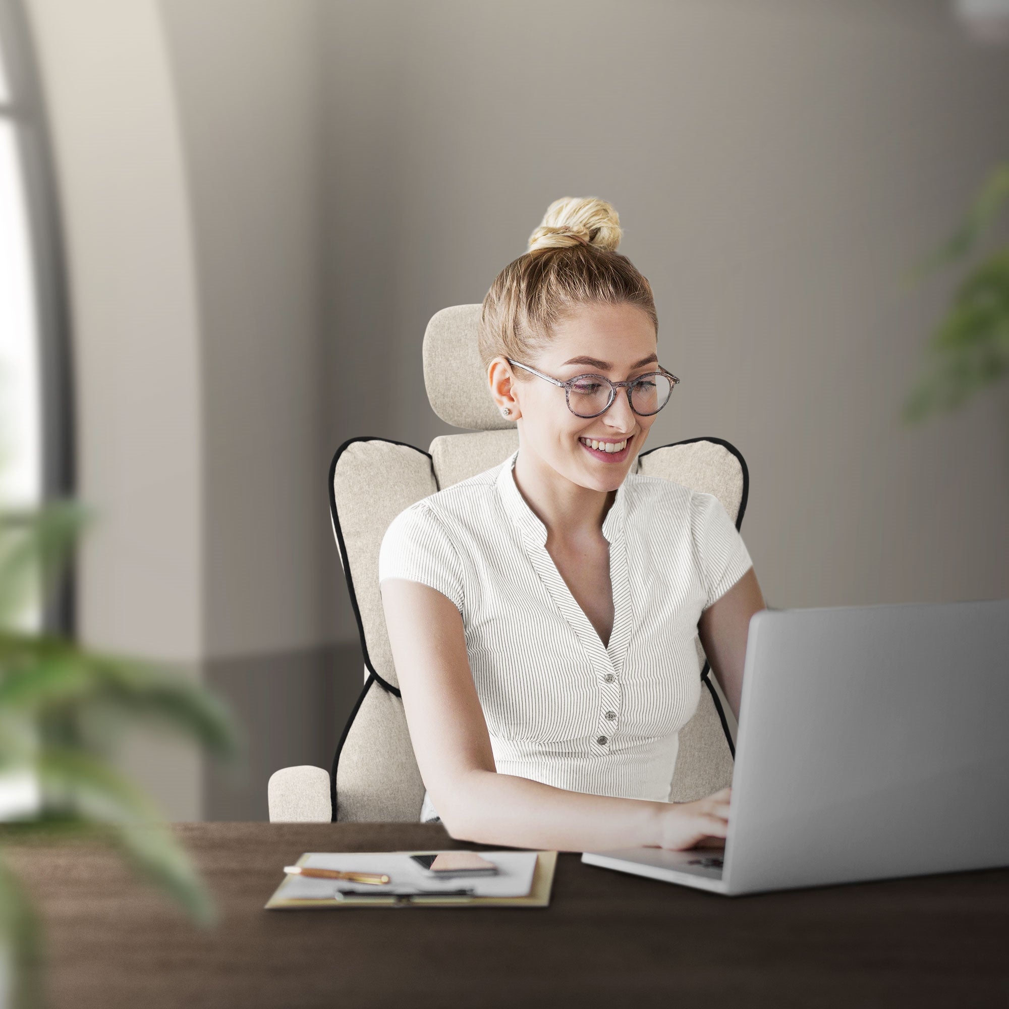Frau sitzt an einem Tisch und arbeitet am Laptop, lächelt dabei.
