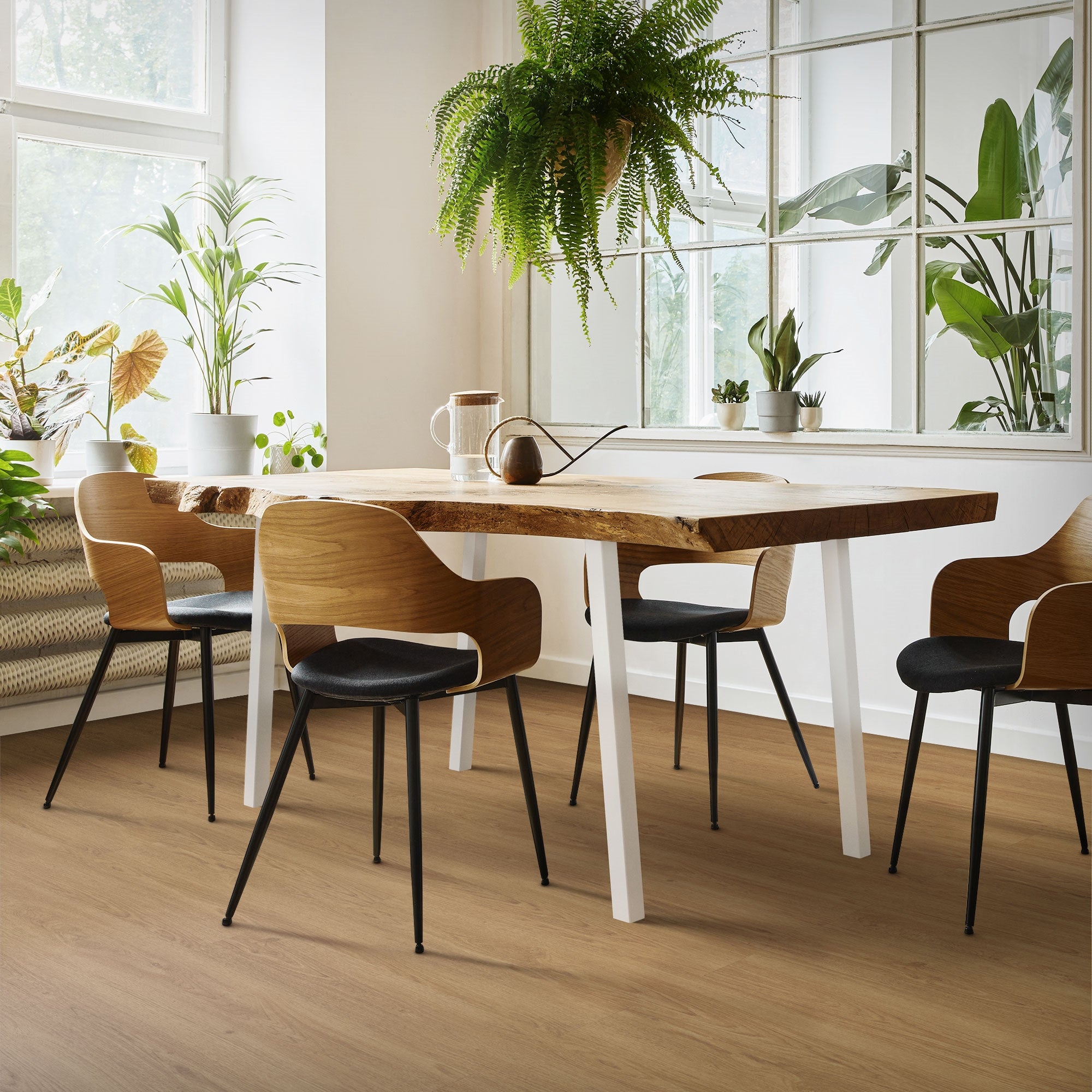 Ein Essbereich mit einem Holztisch und mehreren Stühlen, umgeben von Pflanzen.