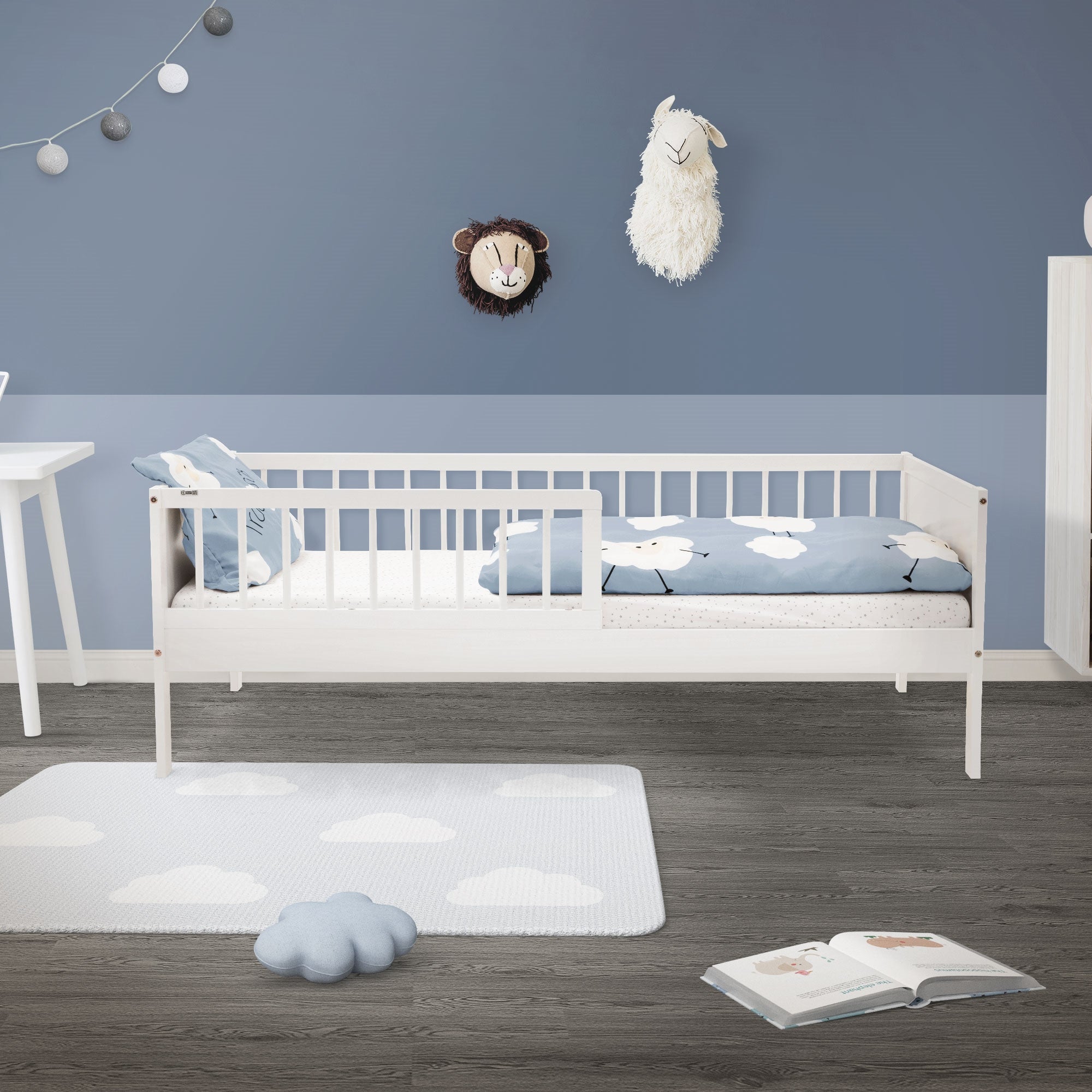 Kinderzimmer mit Bett, blauer Wand, Wolken-Teppich, Spielzeug und Dekoration.