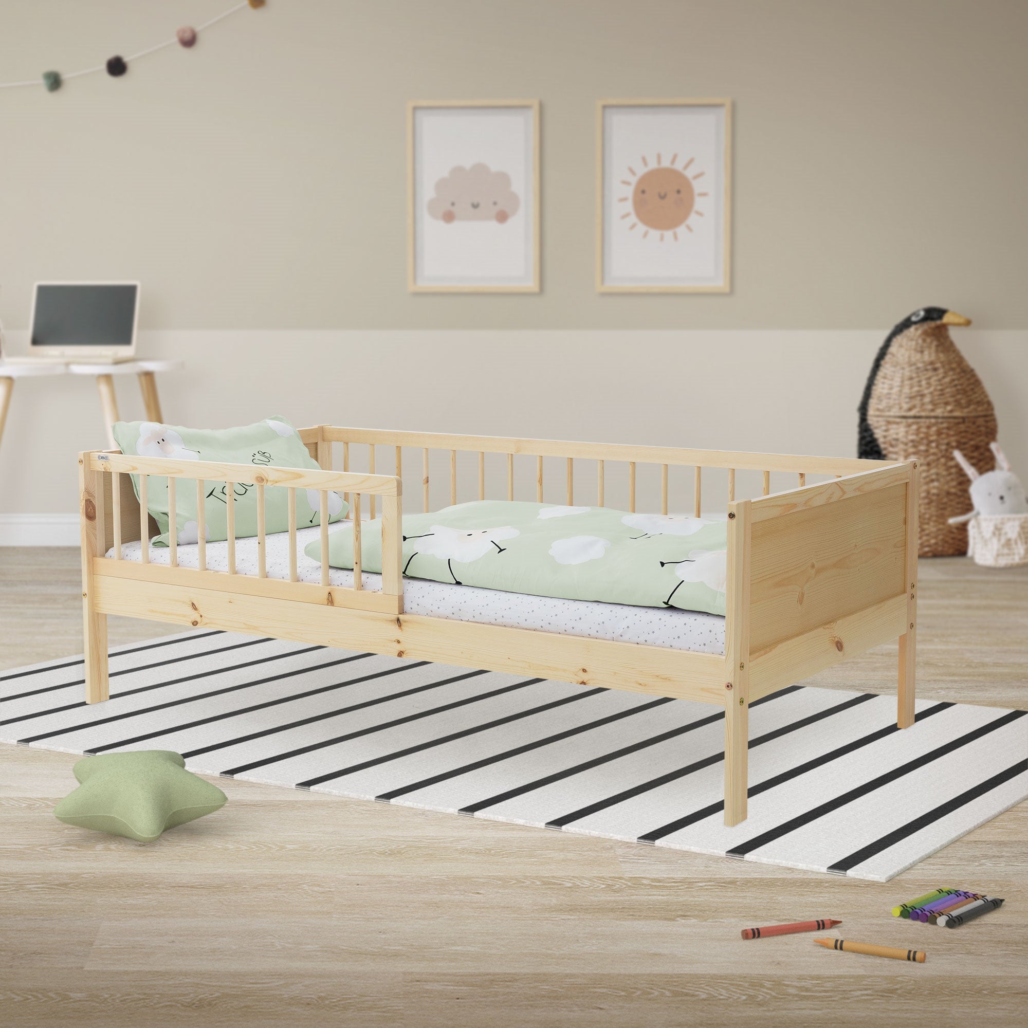 Ein Holz-Kinderbett mit grünem Bettzeug auf einem gestreiften Teppich.