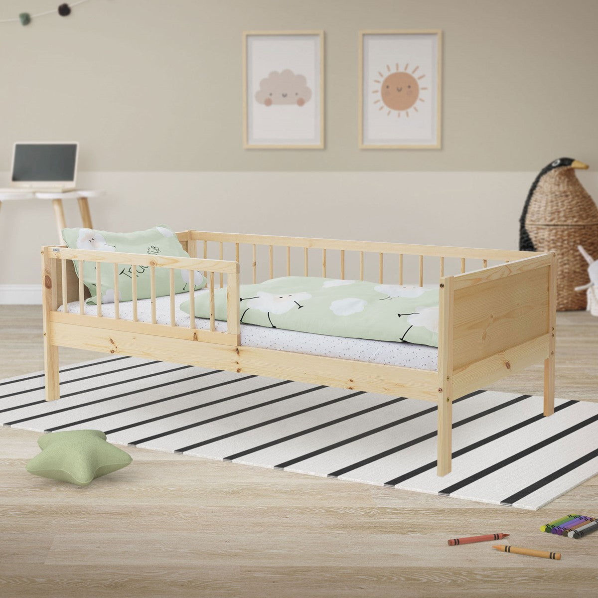 Ein helles Kinderbett aus Holz mit grünem Bettzeug auf einem gestreiften Teppich.