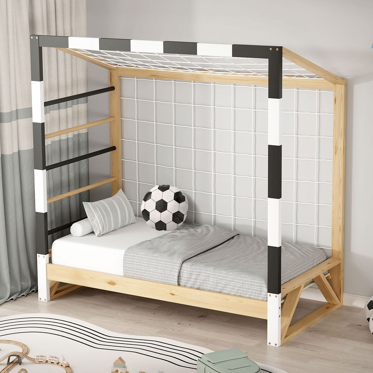 Holz-Kinderbett mit Gitter, grauer Bettwäsche und Fußball auf dem Bett.