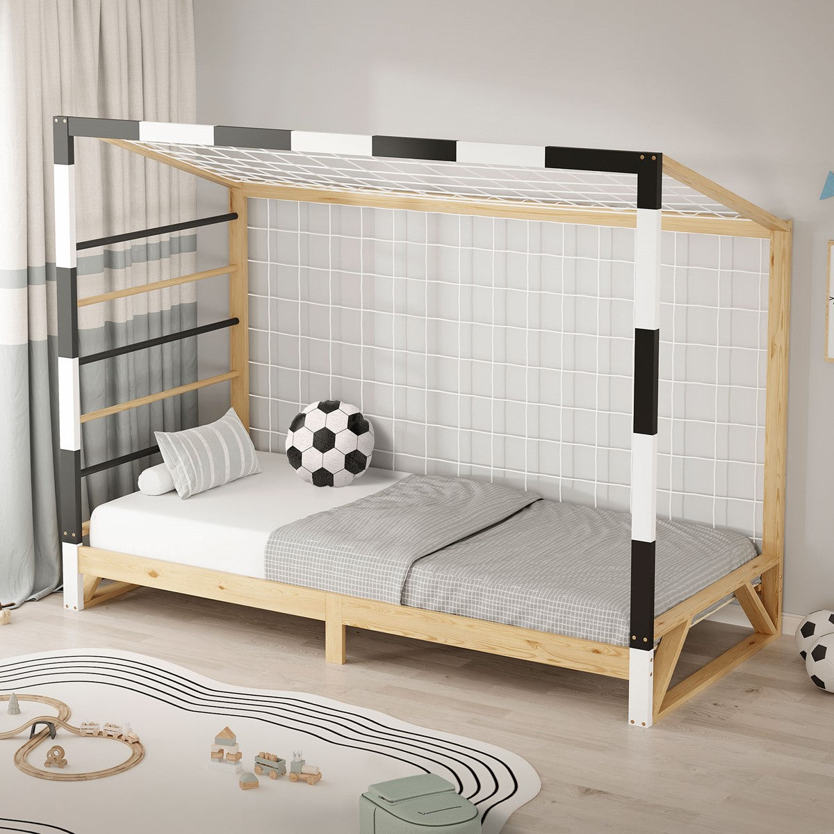 Lit pour enfant avec une structure de toit en bois et des montants rayés noir et blanc, recouvert d’une couverture grise et accompagné d’un coussin en forme de ballon de football.
