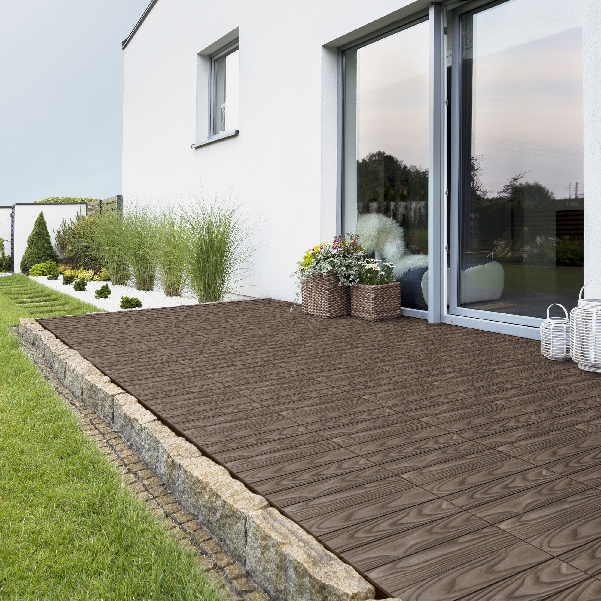 Terrasse mit WPC Fliesen, Pflanzen und großen Fenstern.