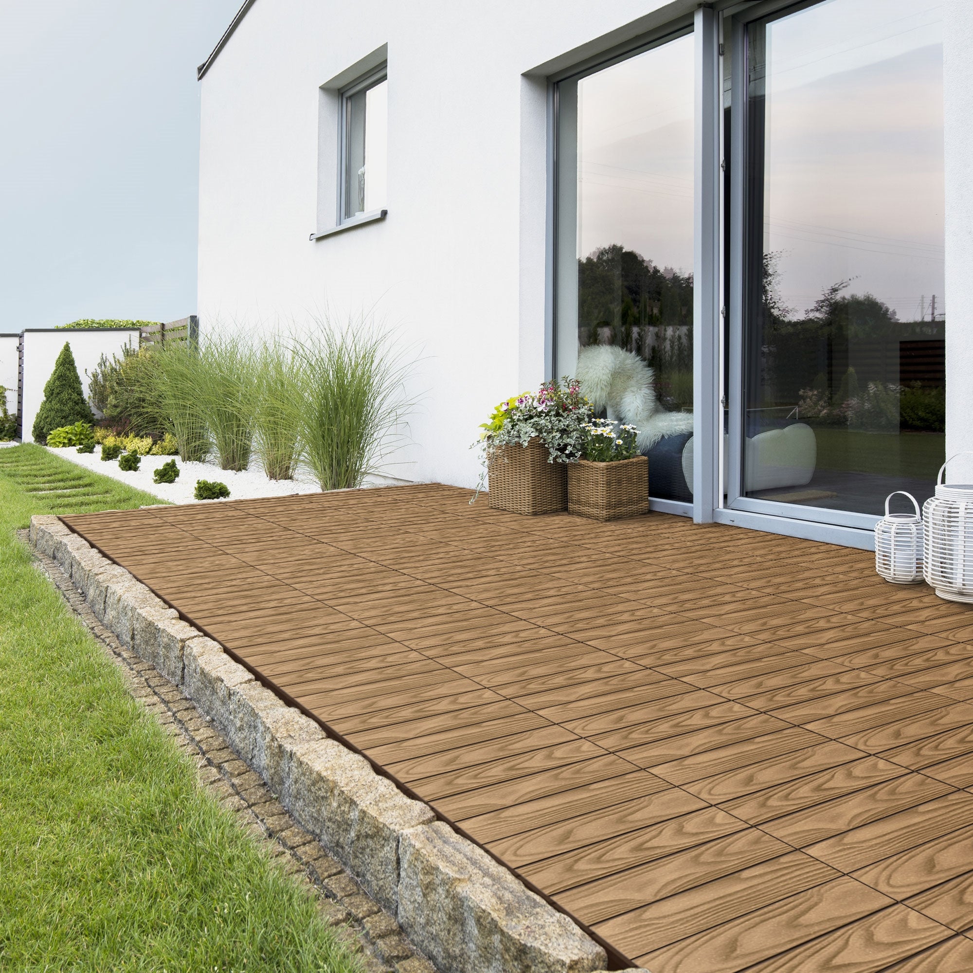 Terrasse mit Holzoptik-Fliesen, Pflanzen und Fensterfront.