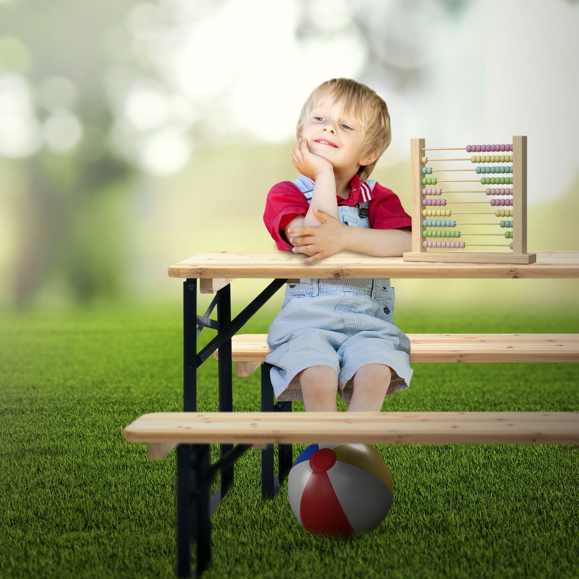 Kind sitzt an einem Tisch im Freien, mit einem Ball und Abacus.